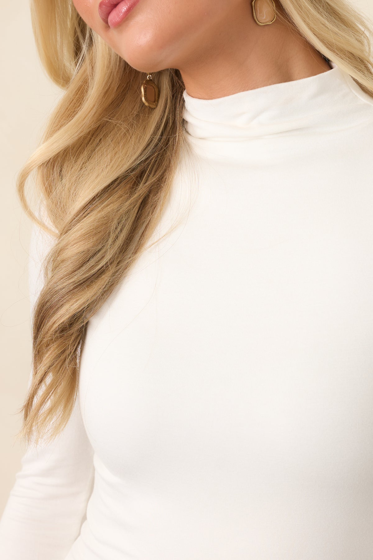 Close view highlights the smooth stretch knit and softly structured mock neckline of the fitted top.