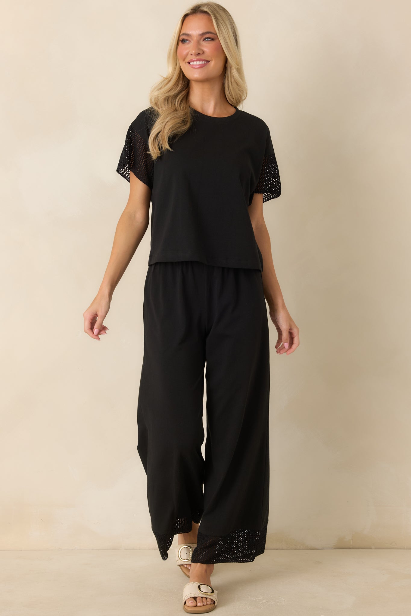 Soft black cropped top designed with a classic crew neckline, relaxed boxy shape, and crochet-accented short sleeves.