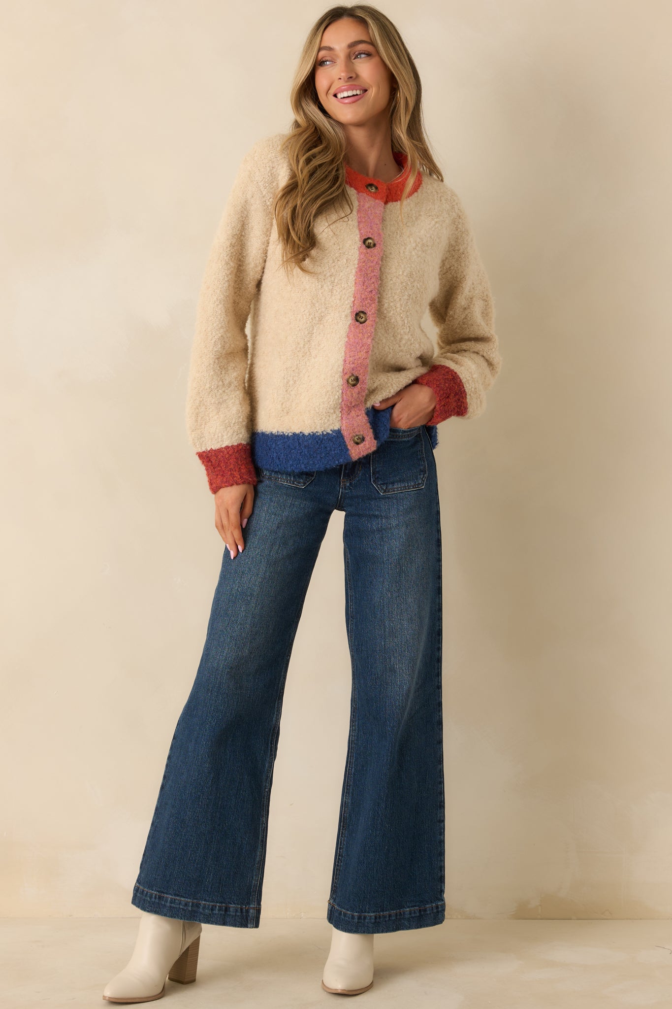 The cardigan displays its soft boucle knit with ivory and multicolor blocks, long sleeves, and full button-up front.