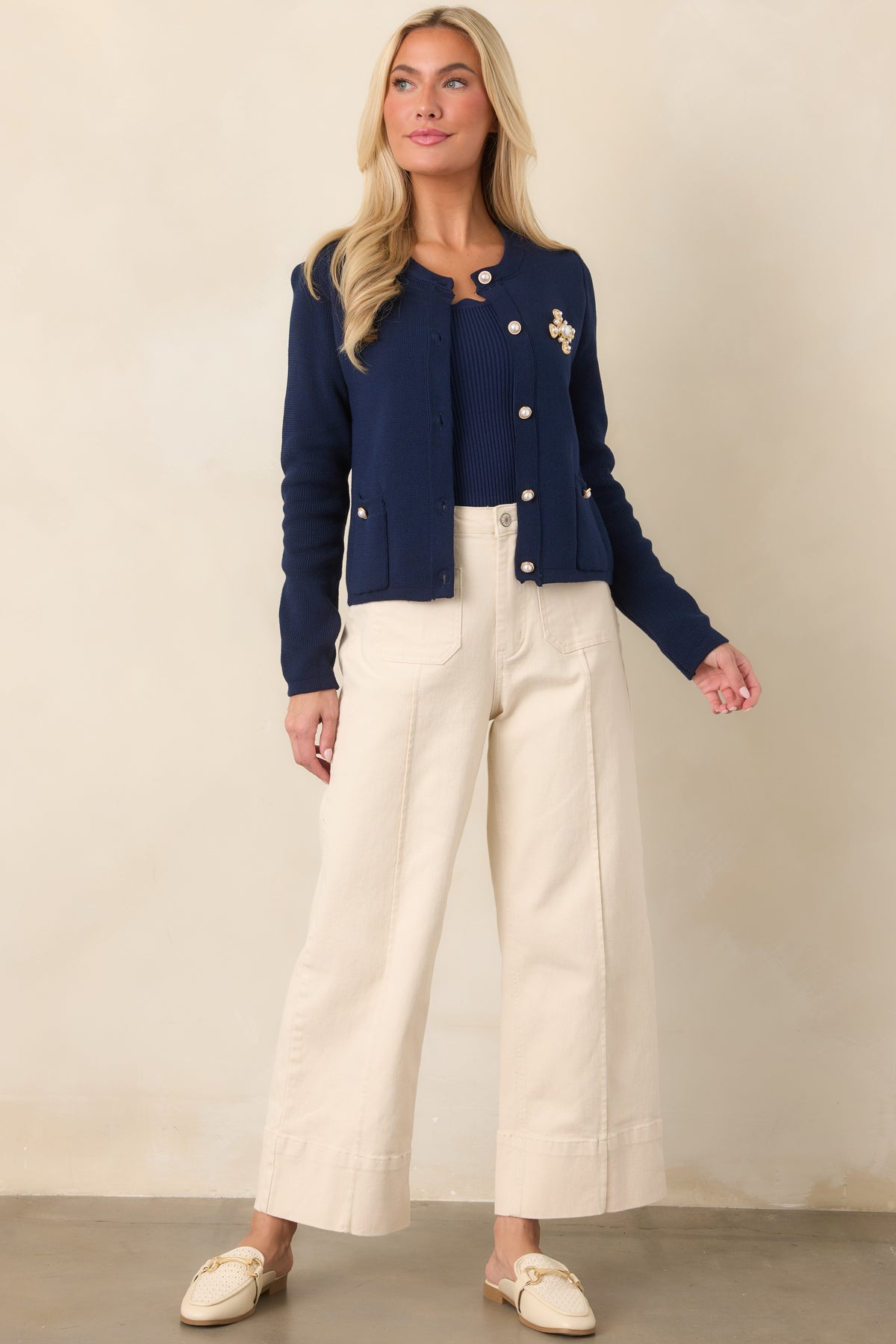 Soft cotton knit cardigan featuring a classic crew neckline, long sleeves, pearl-inspired gold-tone buttons, front patch pockets, and delicate scalloped trim.