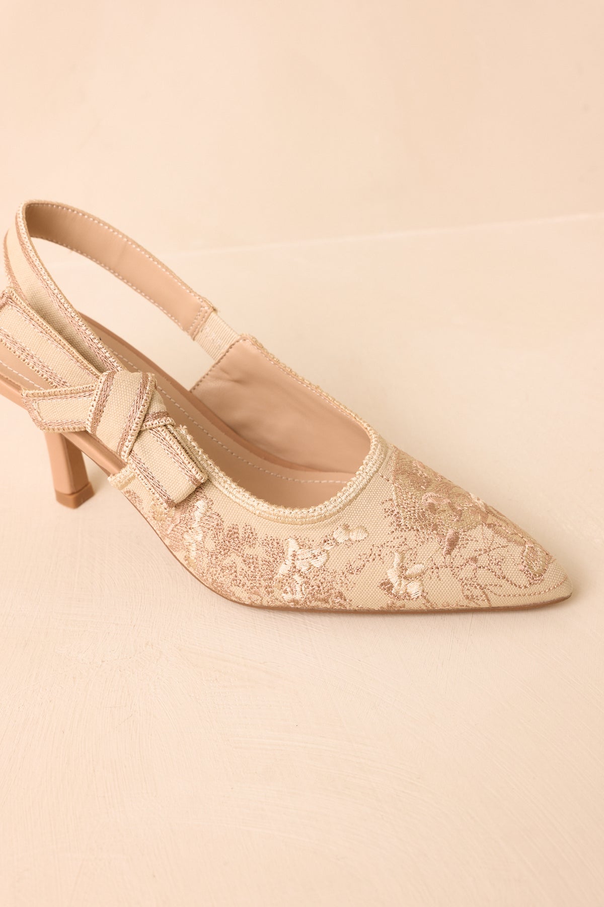 Pointed-toe soft gold heels featuring embroidered uppers, contrast accents, and elevated mid-height heels.
