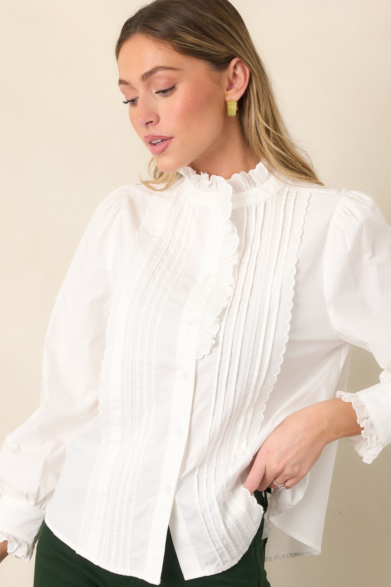 Soft ivory fabric highlights the gathered sleeve cuffs, flowing long sleeves, and relaxed construction of the blouse.