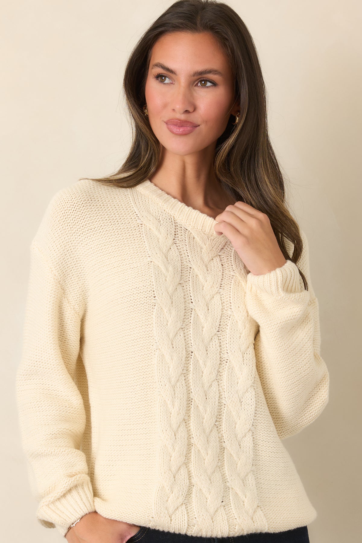 Soft knit ivory sweater with a traditional cable knit pattern extending down the front.