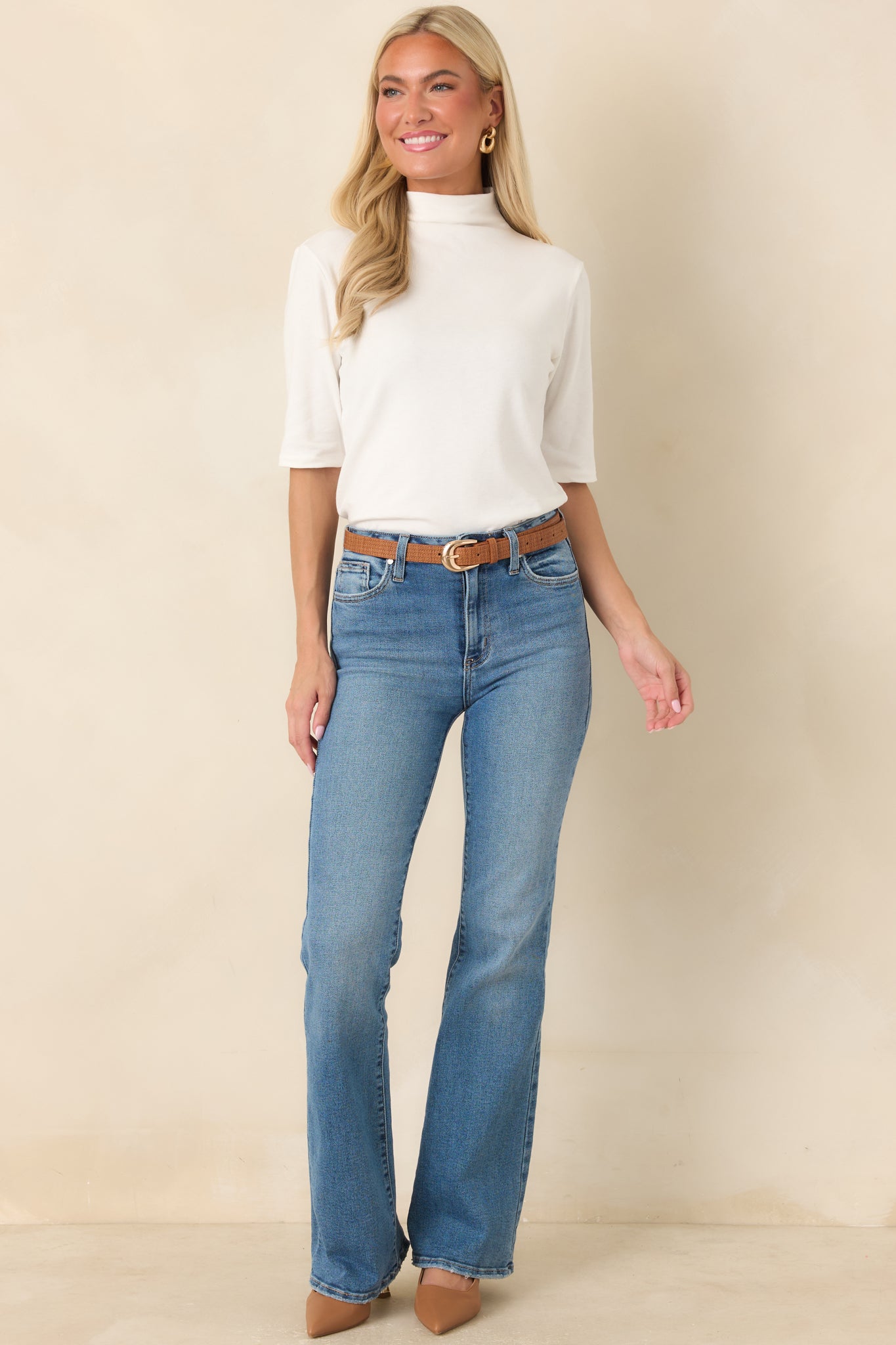 Soft ivory top designed with a classic mock neck, comfortable elbow-length sleeves, and a streamlined fit. The clean knit construction offers a timeless look for layering or wearing on its own.