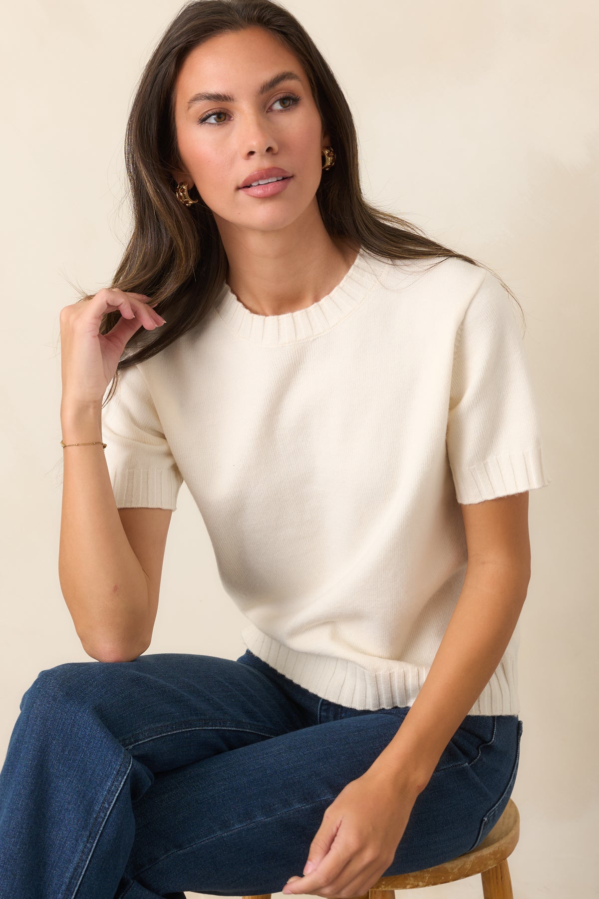 Soft ivory wool-blend top showcasing the classic crew neckline, short sleeves, and ribbed edges at the cuffs and hem.