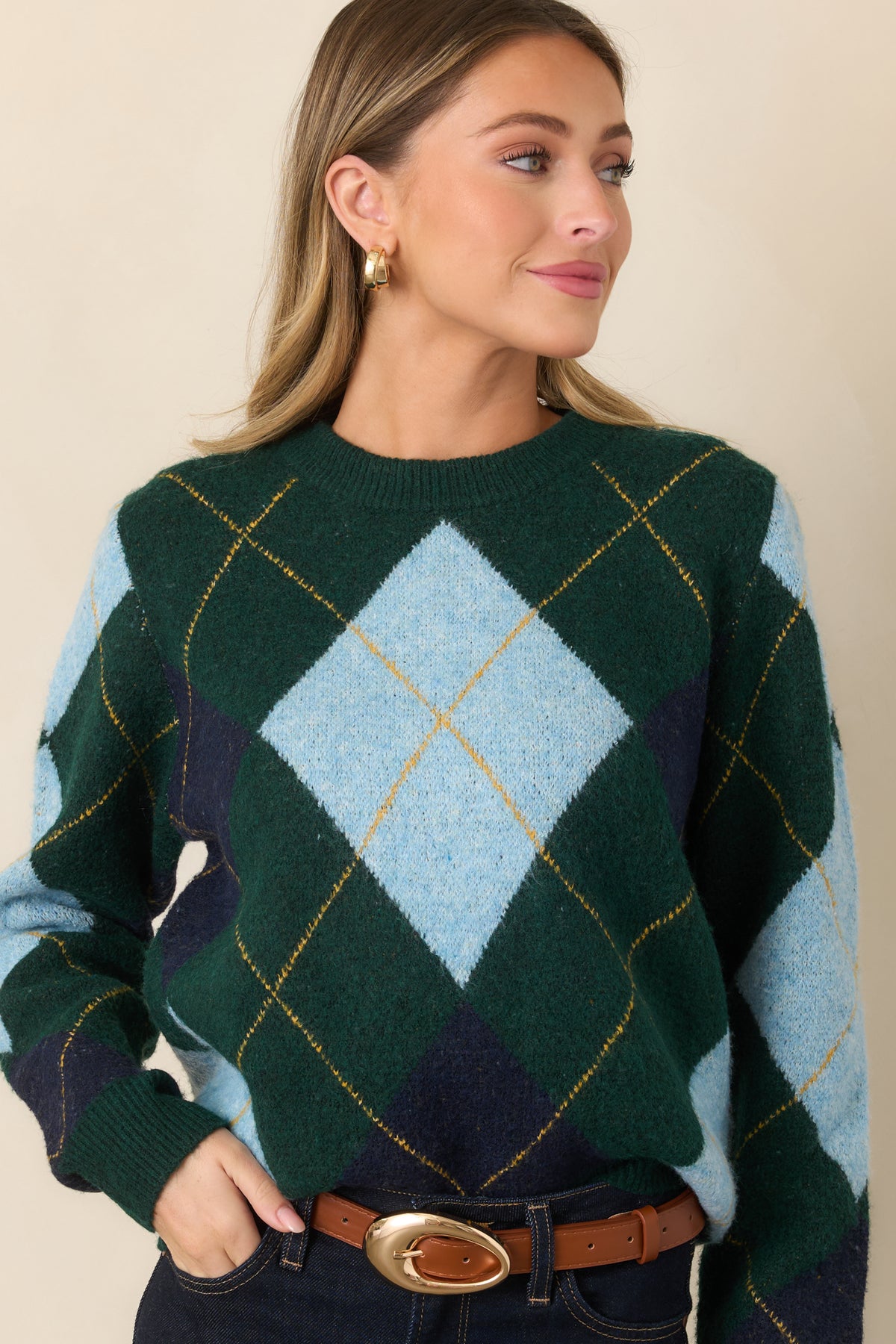 Soft knit top showcasing fine golden yellow lines woven between contrasting diamond accents and a neatly ribbed crew neckline.