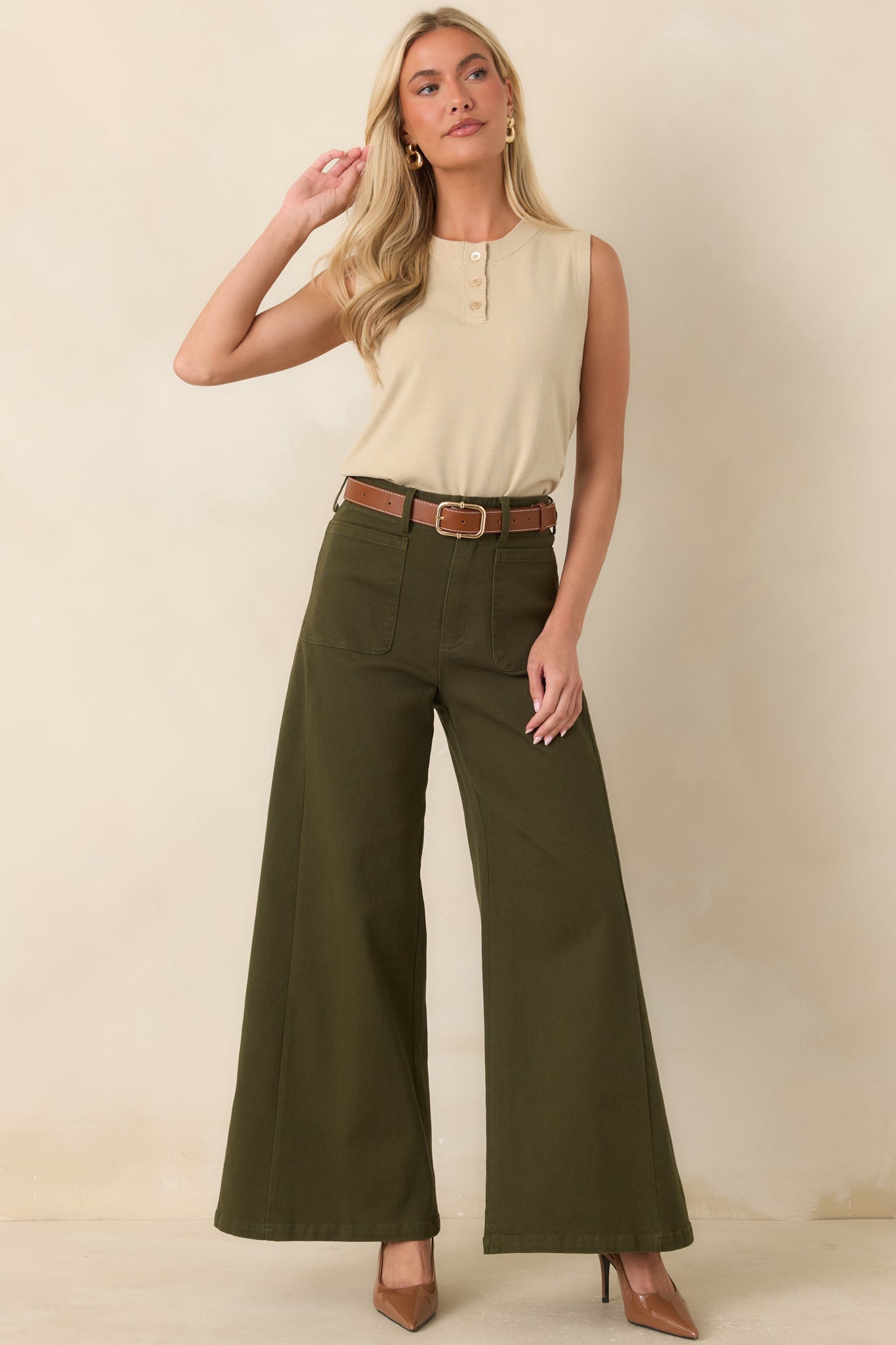 Soft knit sleeveless sweater top with a crew neckline, three-button henley placket, and a relaxed silhouette finished with ribbed trim at the hem.