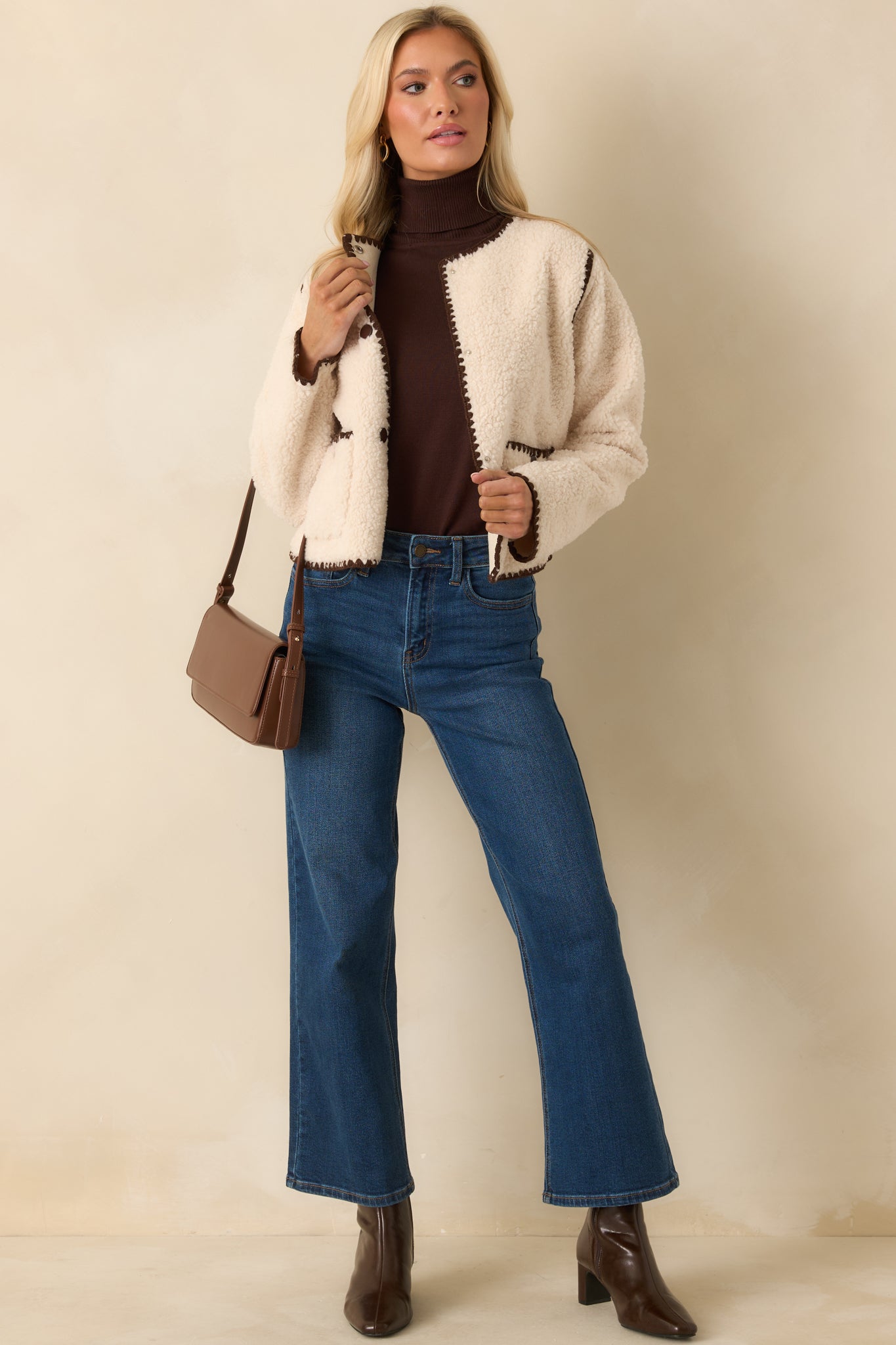 Soft sherpa jacket with brown whipstitch trim and a clean crew neckline.