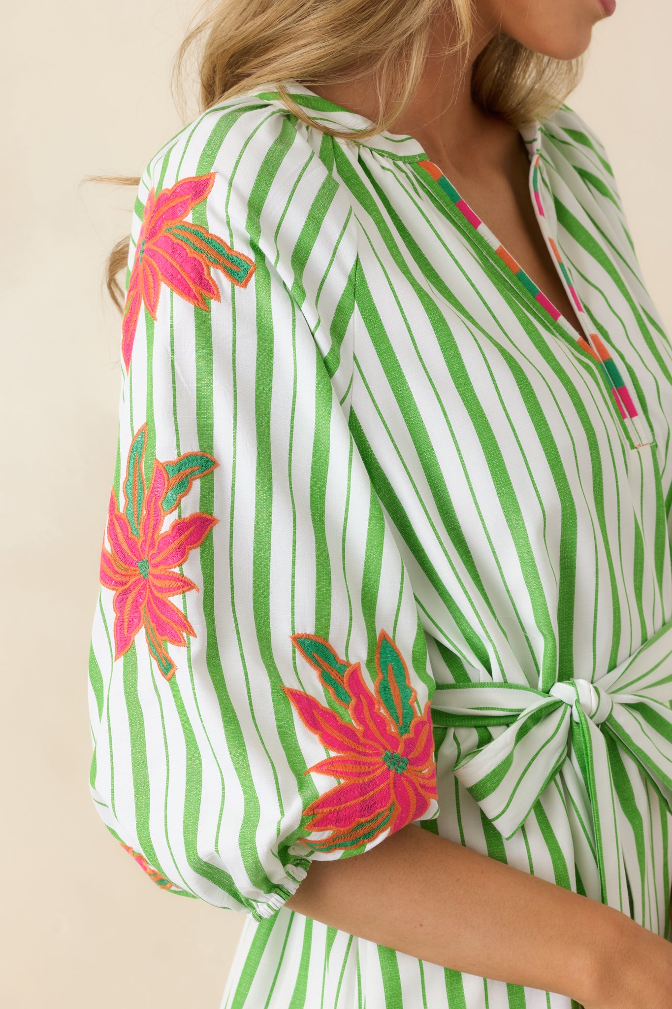 Split neckline with contrast trim and green floral stripe pattern detail.