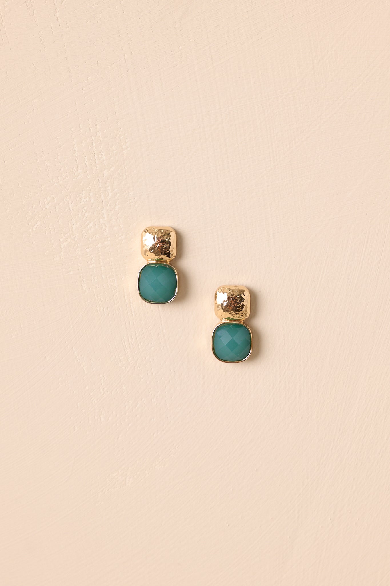 Sleek square earrings in textured gold and vivid green stone shown on a neutral background.