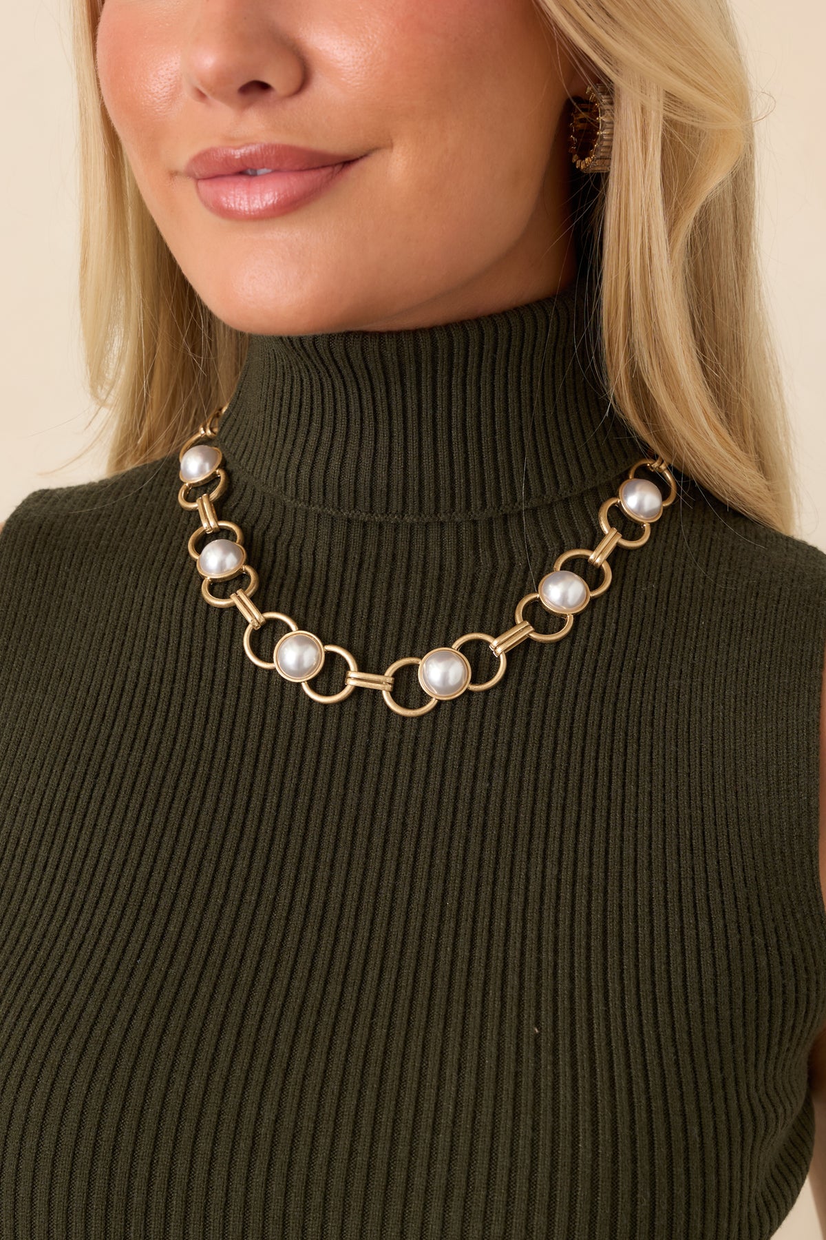 Statement necklace featuring alternating gold-tone chain links and smooth round pearls nestled within select links.