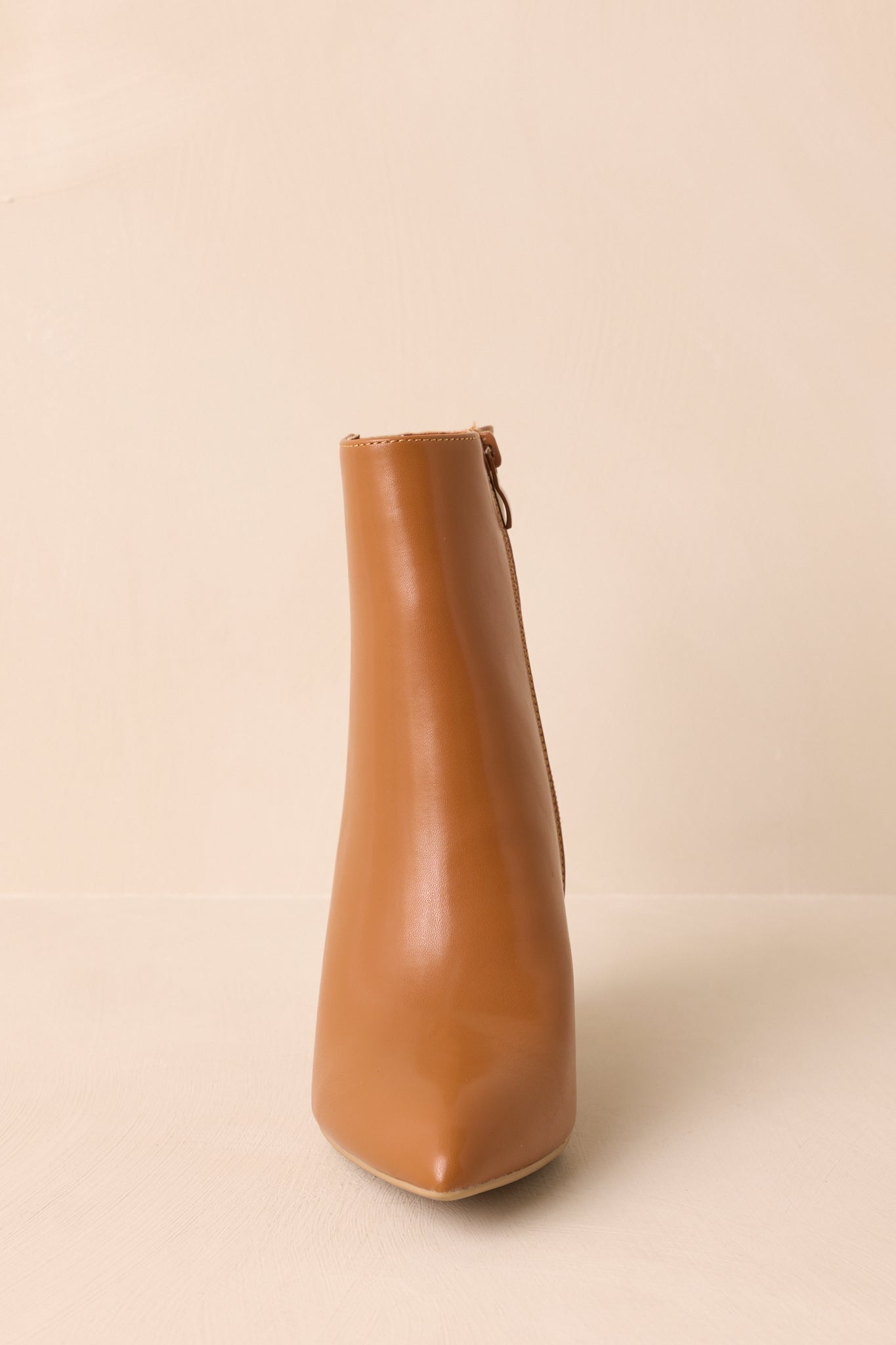 A straight-on front shot of the caramel brown ankle boots capturing the pointed toe and glossy finish.