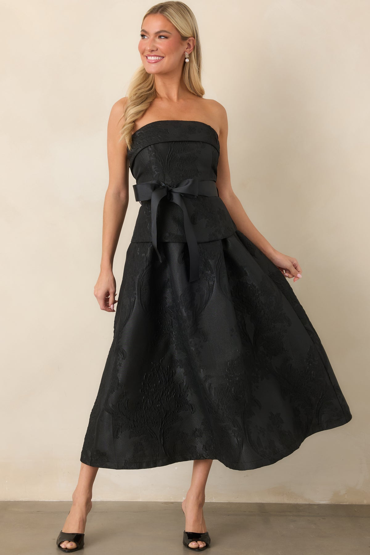 Strapless midi dress with a structured corset-inspired bodice, wide grosgrain sash, and full pleated A-line skirt.