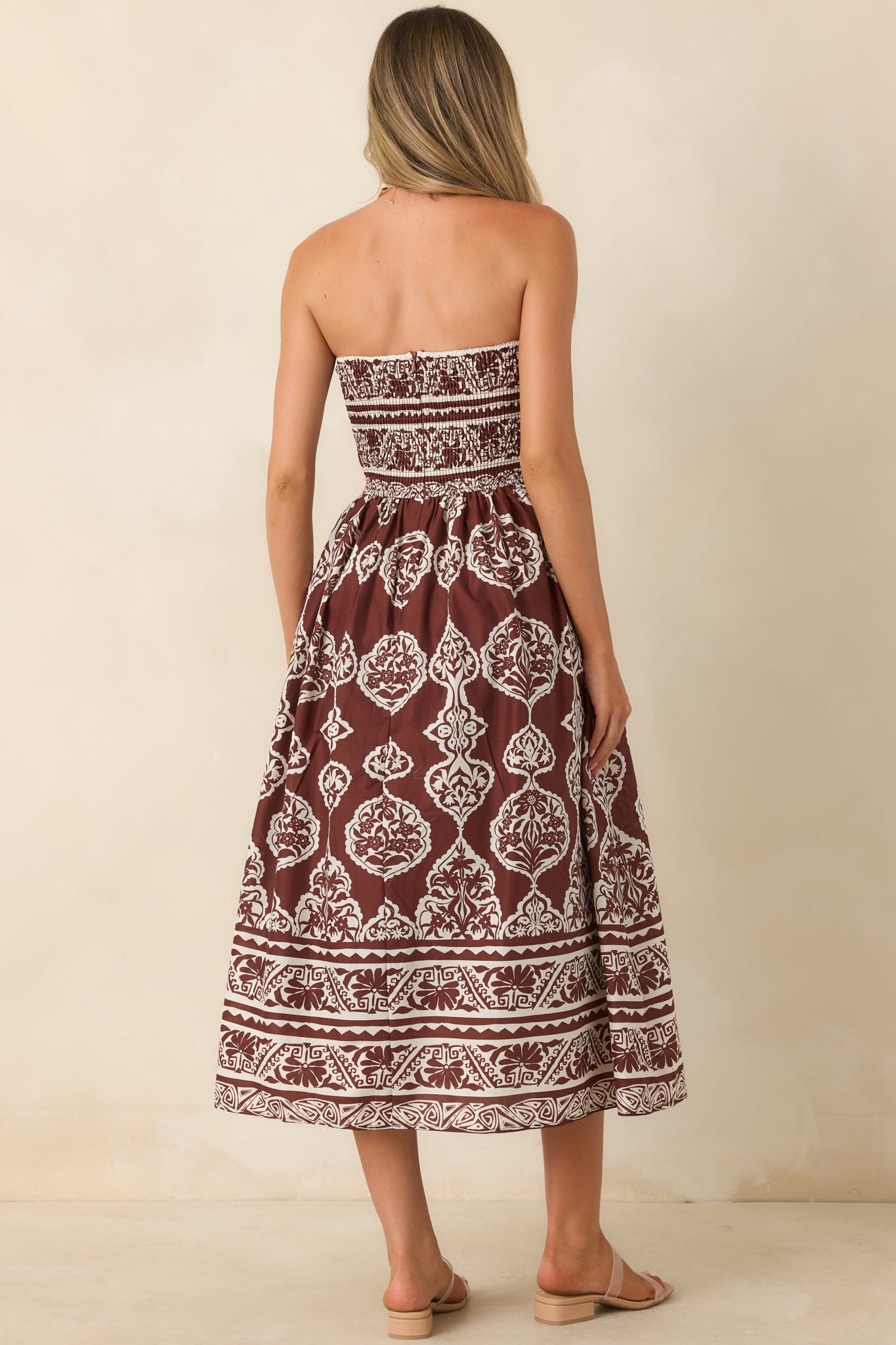 Rear view of the strapless midi dress featuring a smocked back, fitted bodice, and flowing gathered skirt.