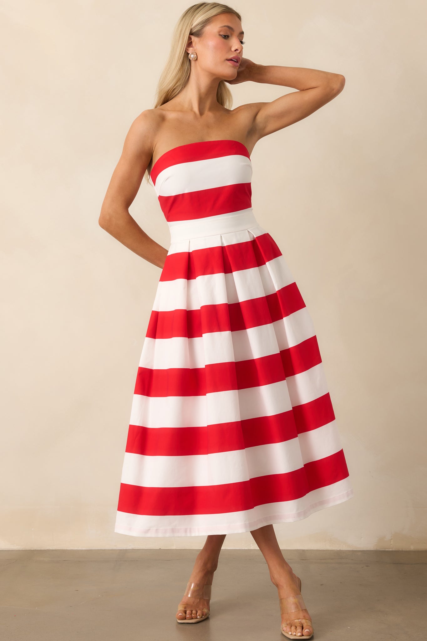 The front view of the strapless red and white striped dress with a fitted bodice and pleated skirt falling to a flattering length.