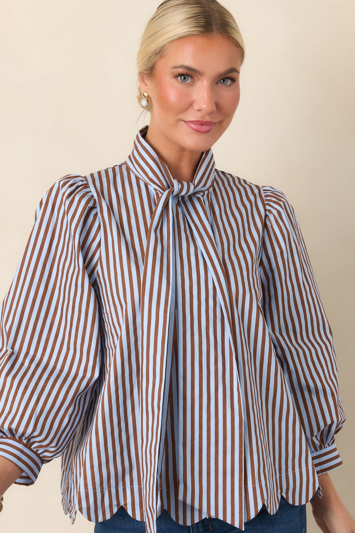 Striped blouse showcasing voluminous three-quarter sleeves and a delicate button-front closure.