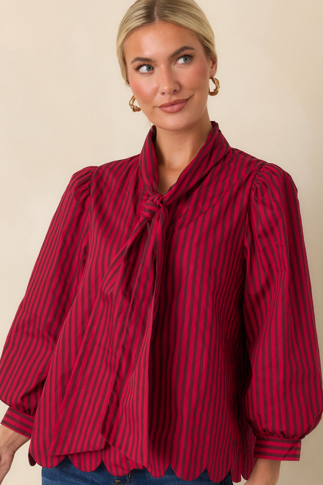 Front detail of the striped blouse showcasing the button-front closure, tie neckline, and feminine shape.