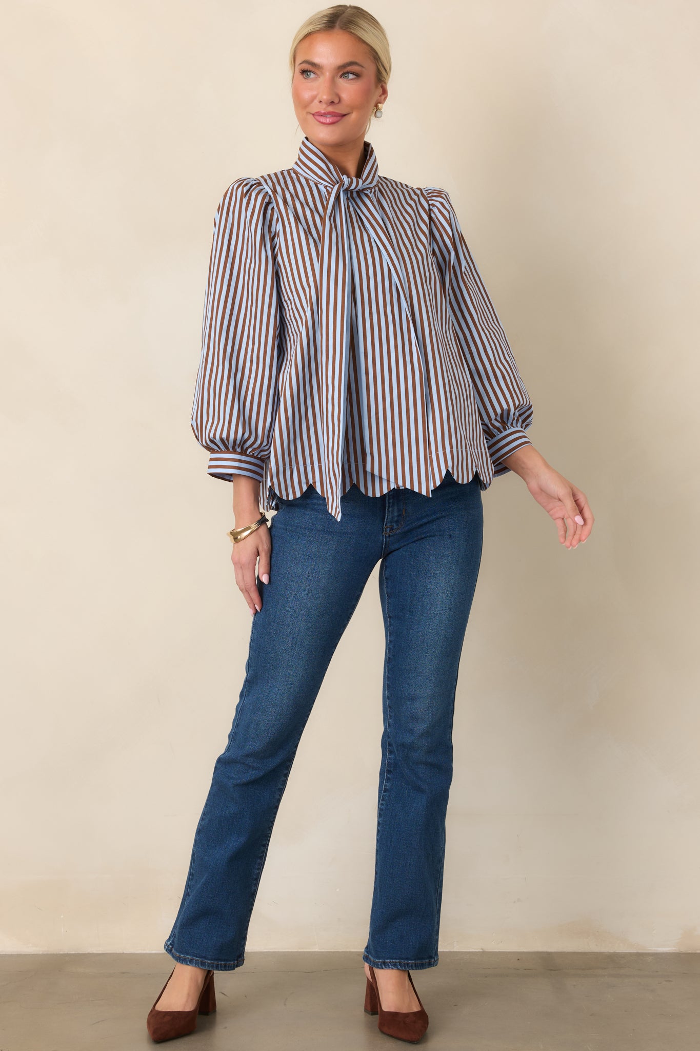 Striped button-front blouse featuring a softly tied neckline, voluminous sleeves, and a feminine scalloped hem.