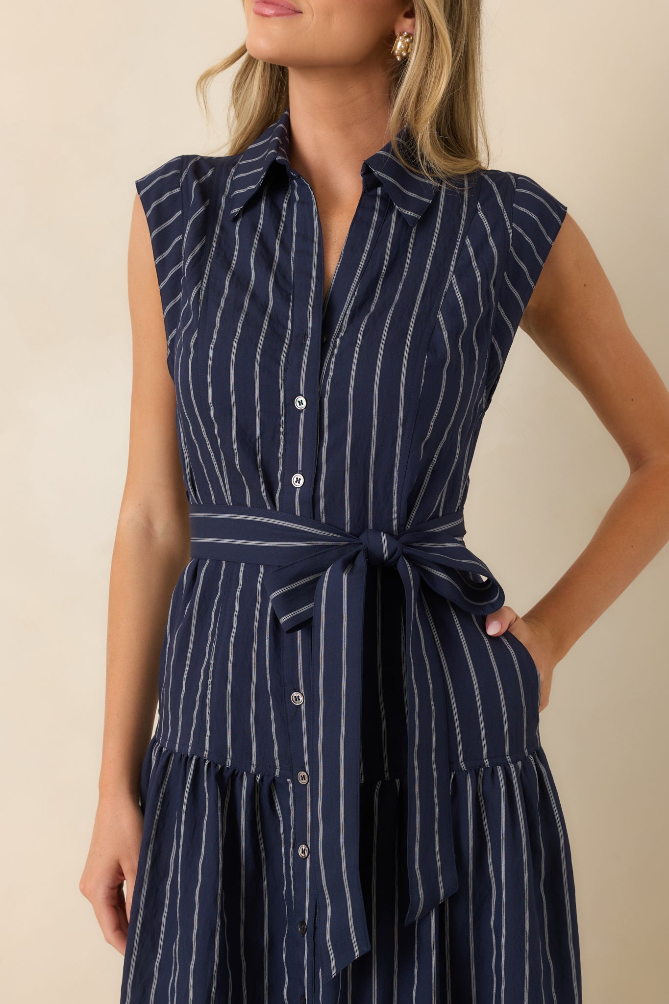 Detailed view of the striped fabric, collared neckline, button-front closure, and removable tie belt.