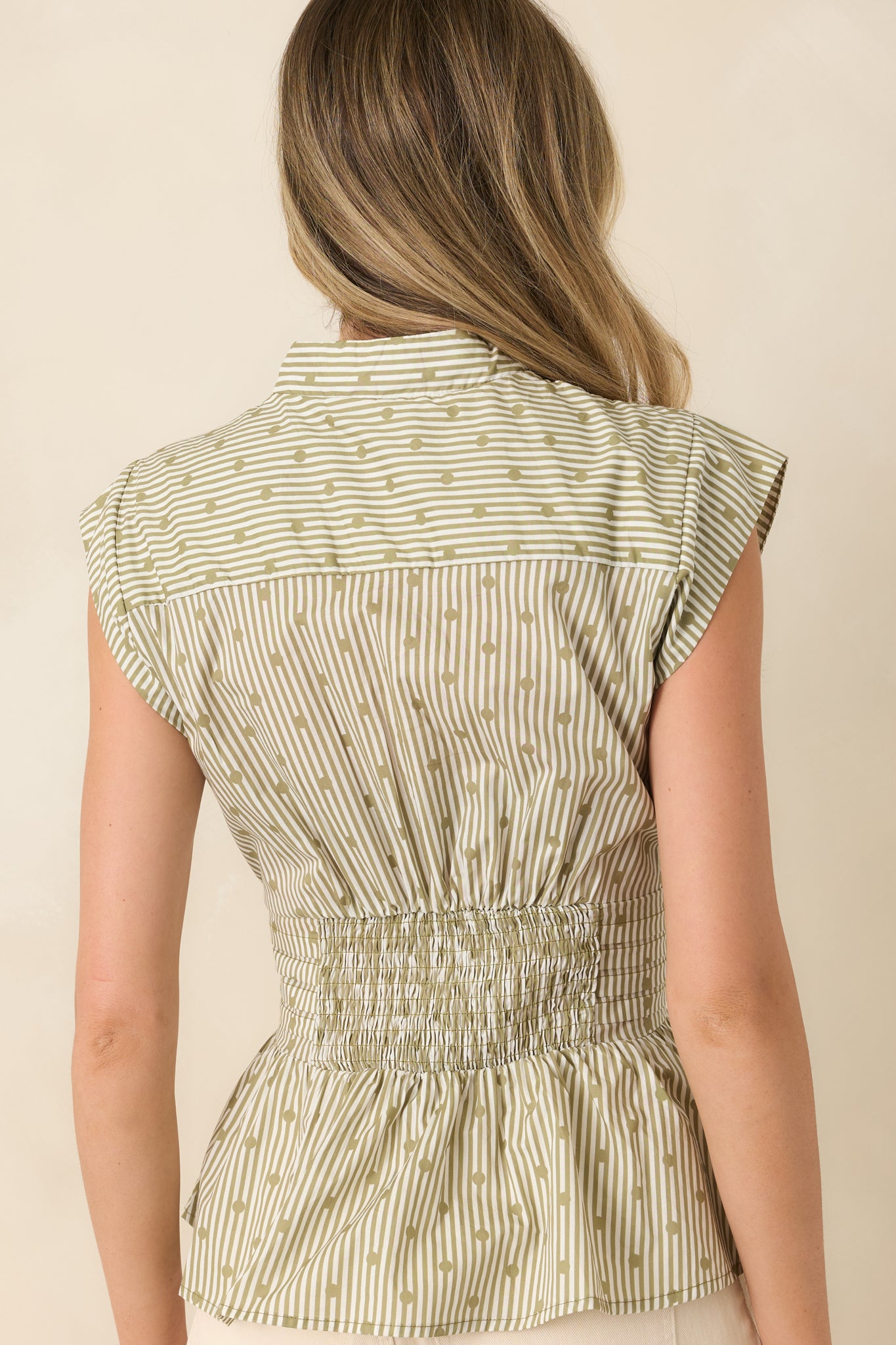 Rear view of the striped cotton blouse featuring cap sleeves and a softly flared peplum silhouette.