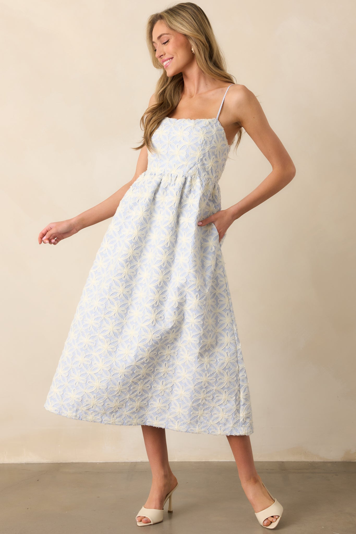 Maxi dress with blue and white stripes and 3D floral appliqués, showcasing the square neckline and adjustable spaghetti straps, offering a graceful, relaxed fit.