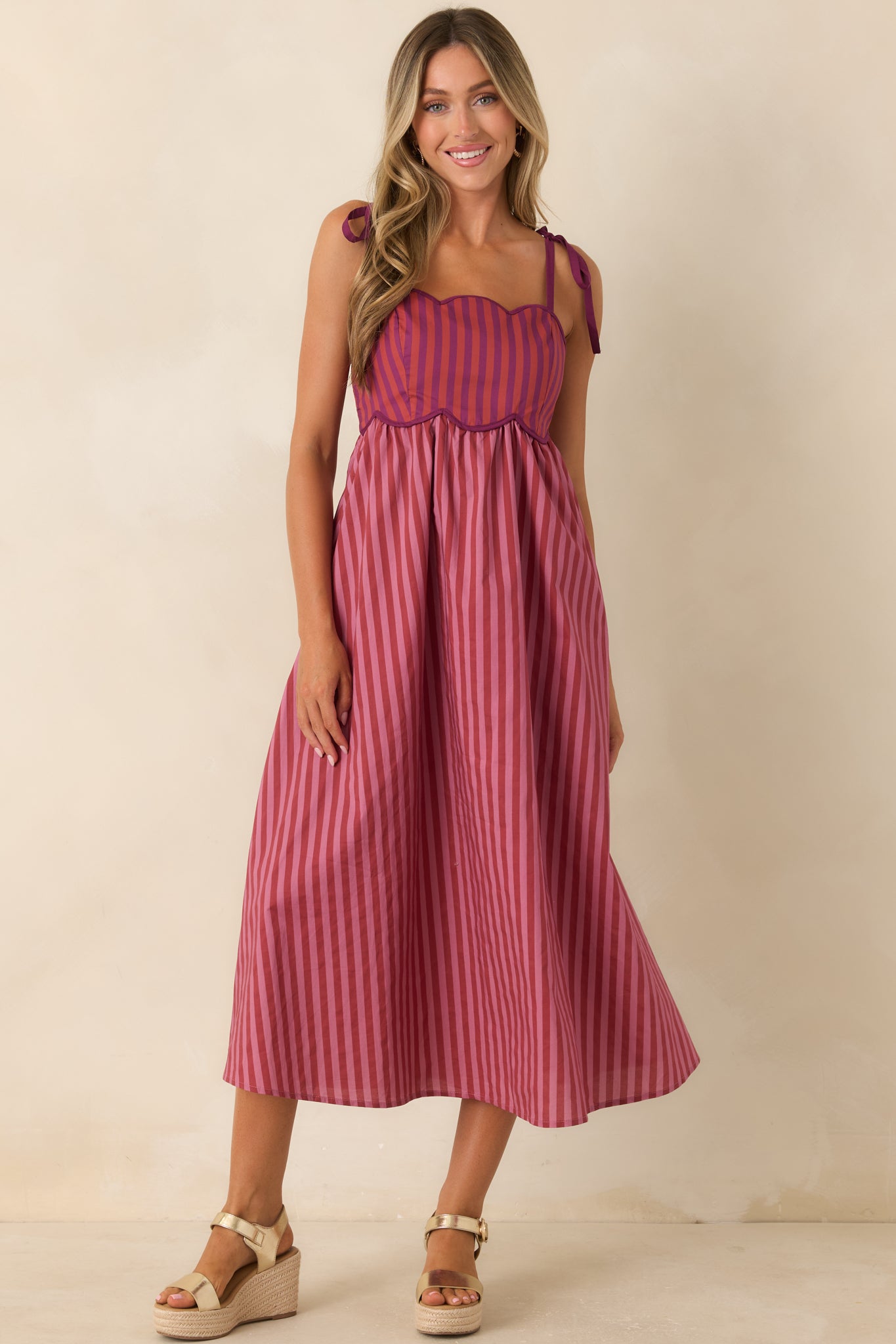 Colorful striped midi dress designed with contrast piping, adjustable shoulder ties, and a flowing silhouette.