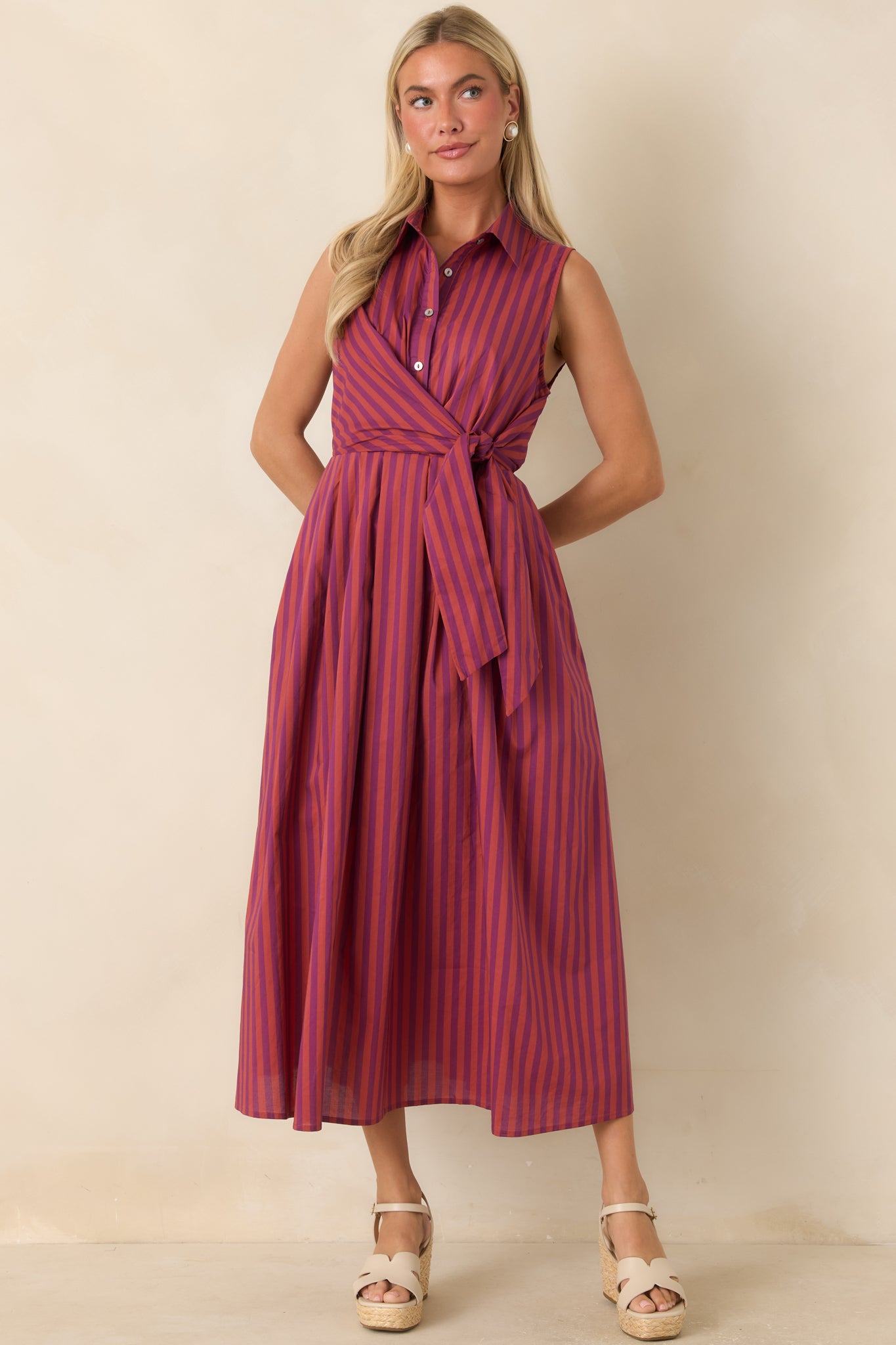 Striped midi shirtdress featuring a sleeveless silhouette, waist-defining front ties, and a softly flowing full skirt.
