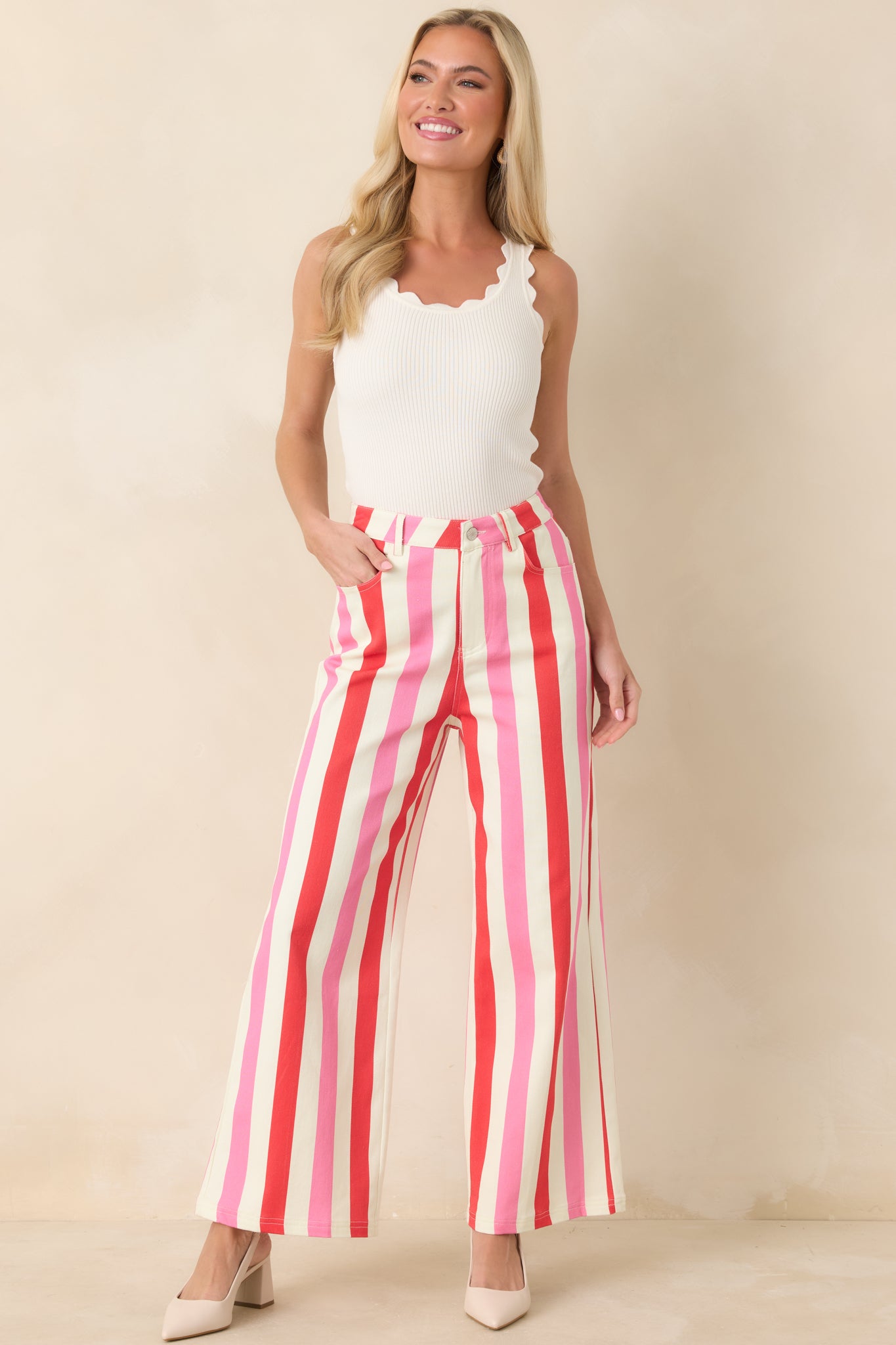 White, red, and pink striped pants with high-rise waist, wide leg silhouette, and vertical stripes.