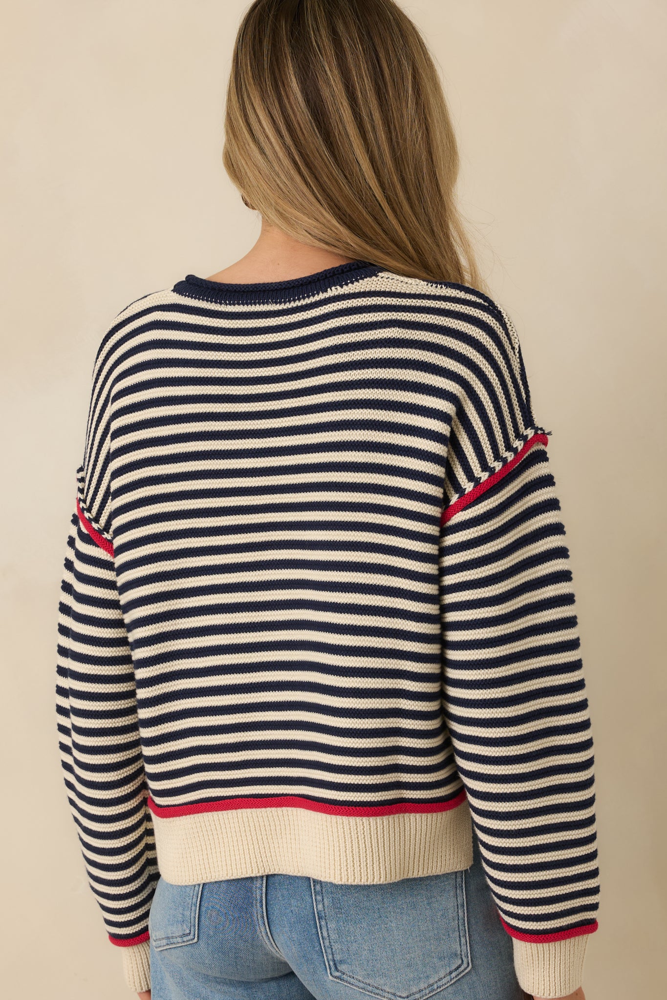 Navy stripe sweater displaying the relaxed silhouette from the rear with horizontal stripes, ribbed hem, and long sleeves.