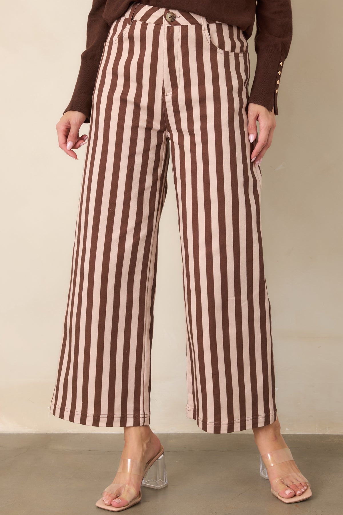 Detailed view of the cropped pants’ structured silhouette, high-rise waistband, and alternating brown and ivory vertical stripes.