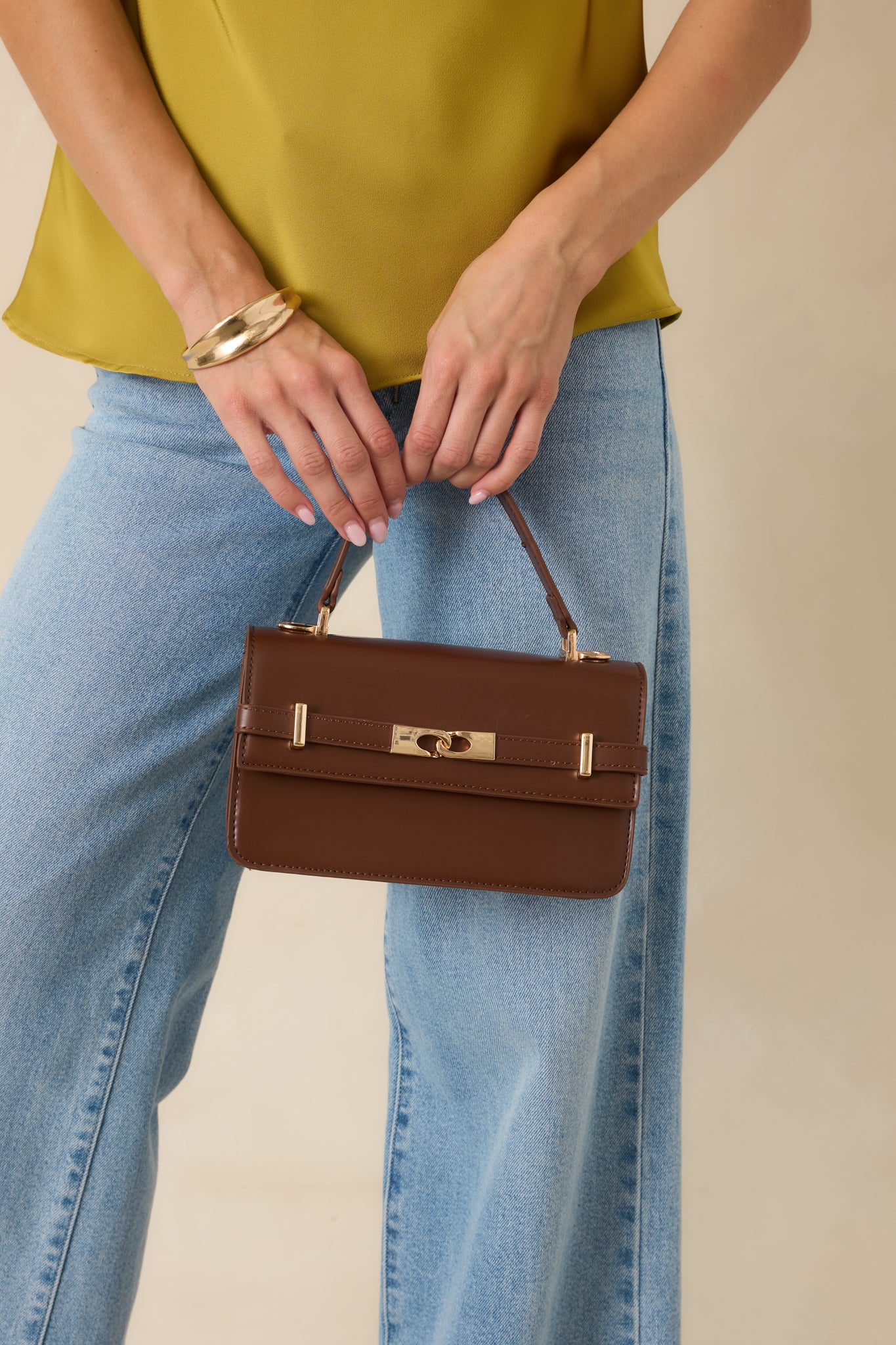 Structured chocolate handbag with polished gold-tone accents, detachable shoulder strap, and a classic everyday design.