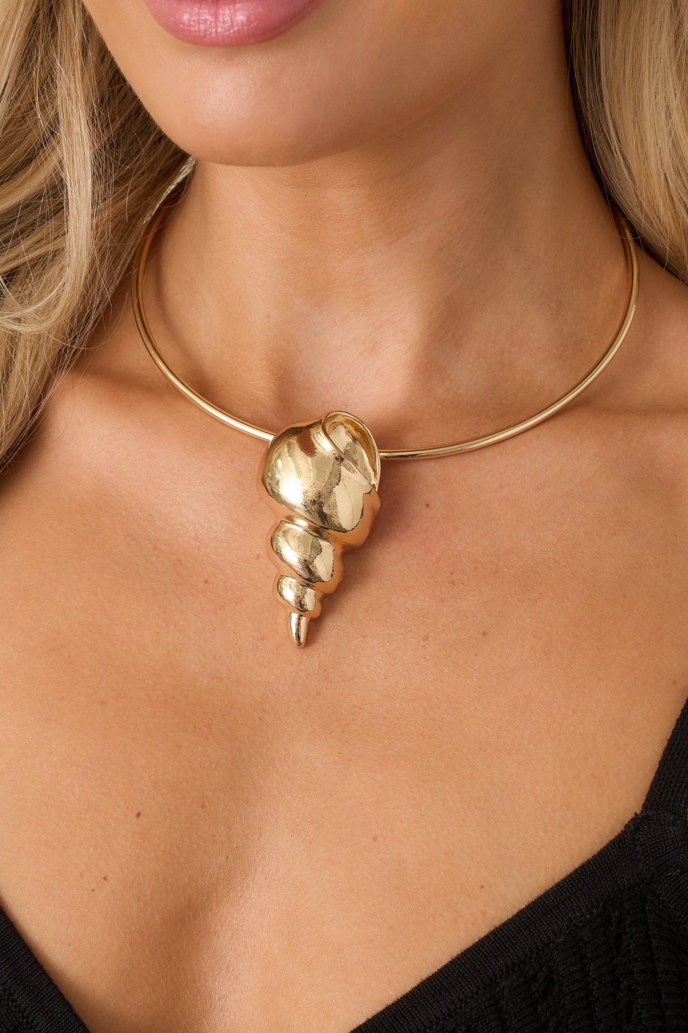 Statement gold necklace showcasing a sleek collar silhouette and textured shell pendant detail for an elevated finish.