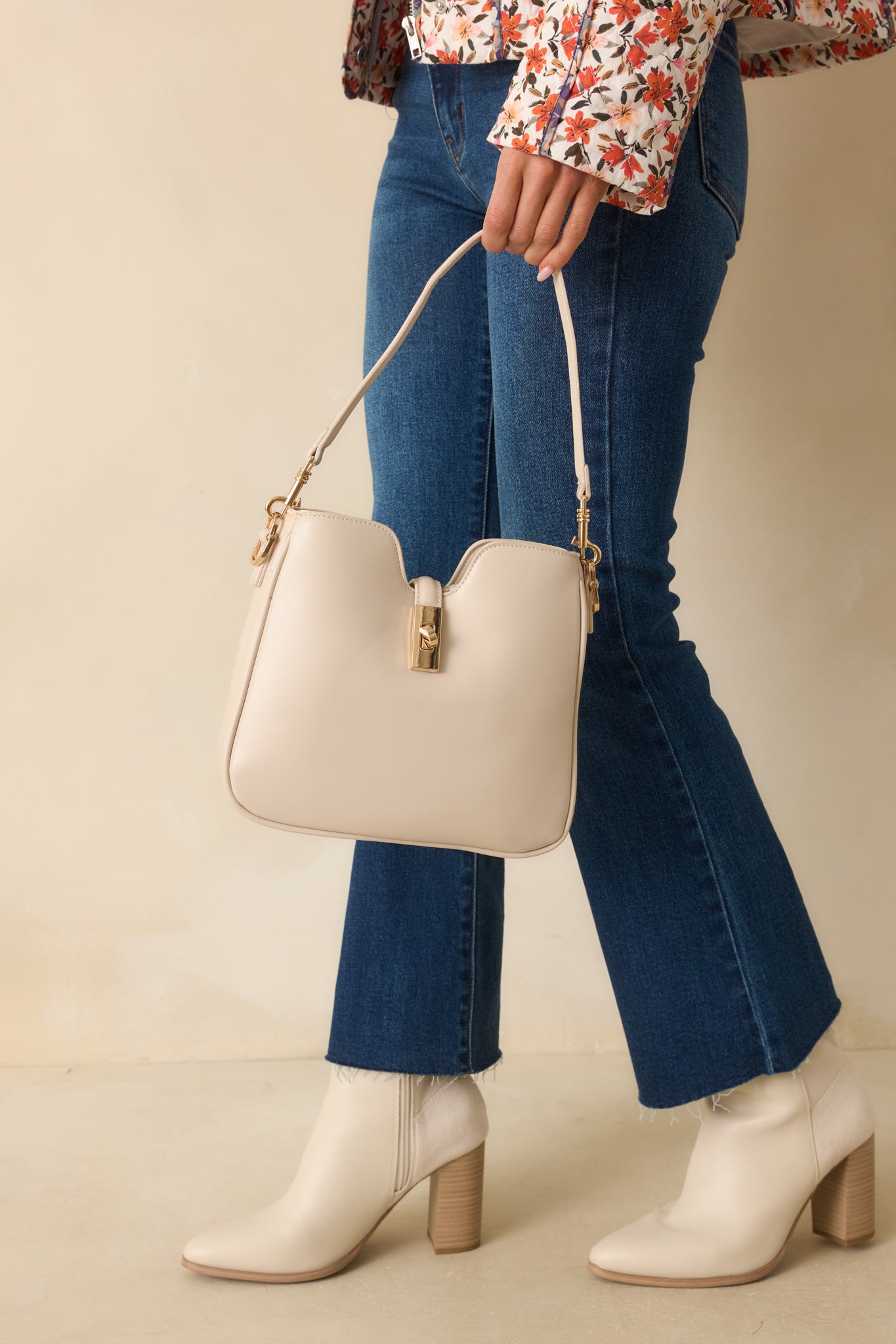 Structured ivory faux leather bag with optional shoulder and adjustable crossbody straps and a v-cut top edge.
