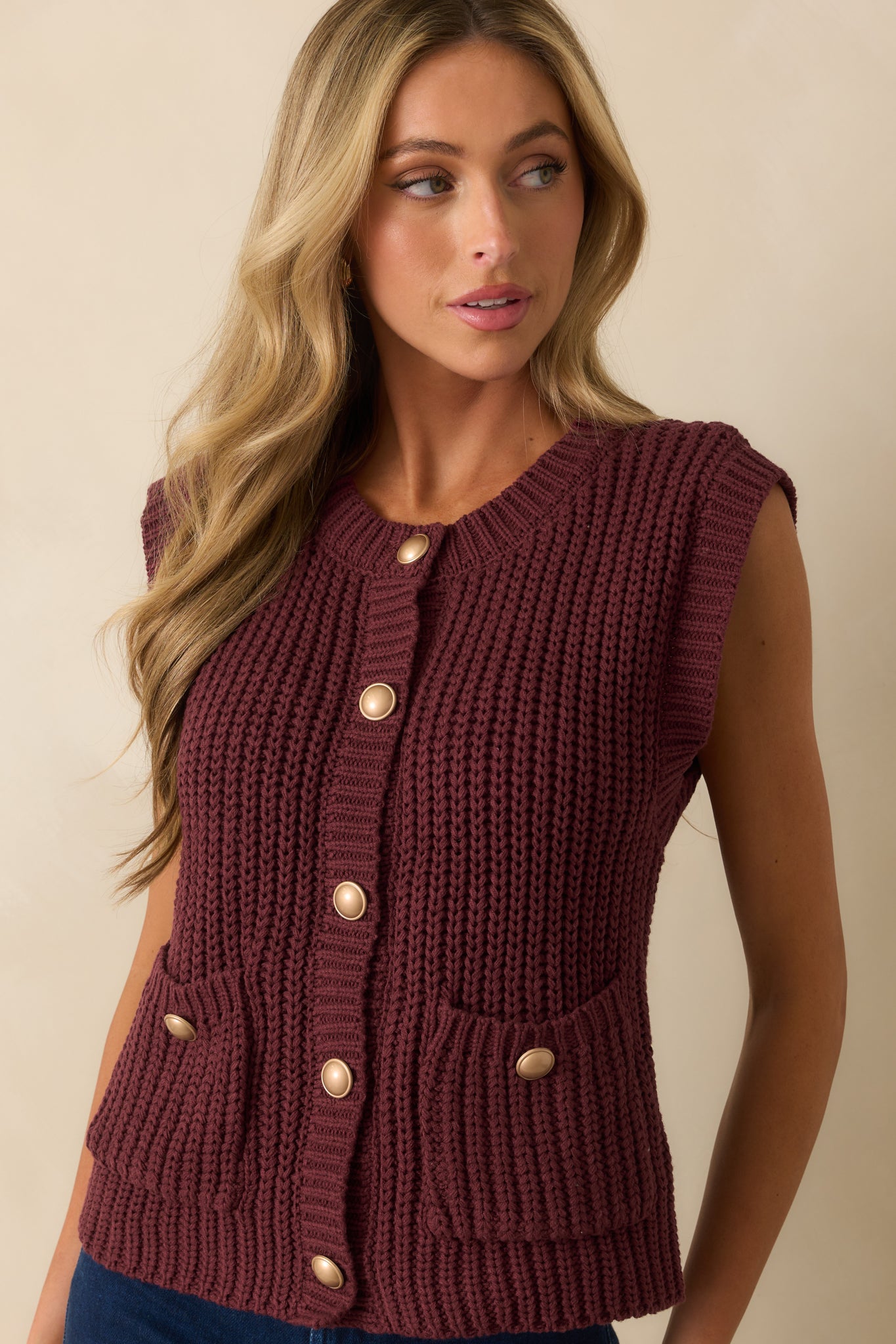 Sweater vest highlighting gold-tone domed buttons and front patch pockets.