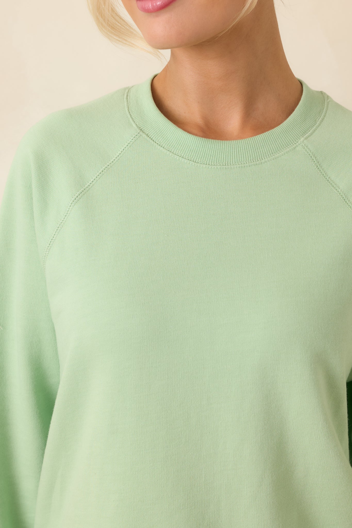 Sweatshirt detail showing raglan sleeve seam and smooth, structured fabric.