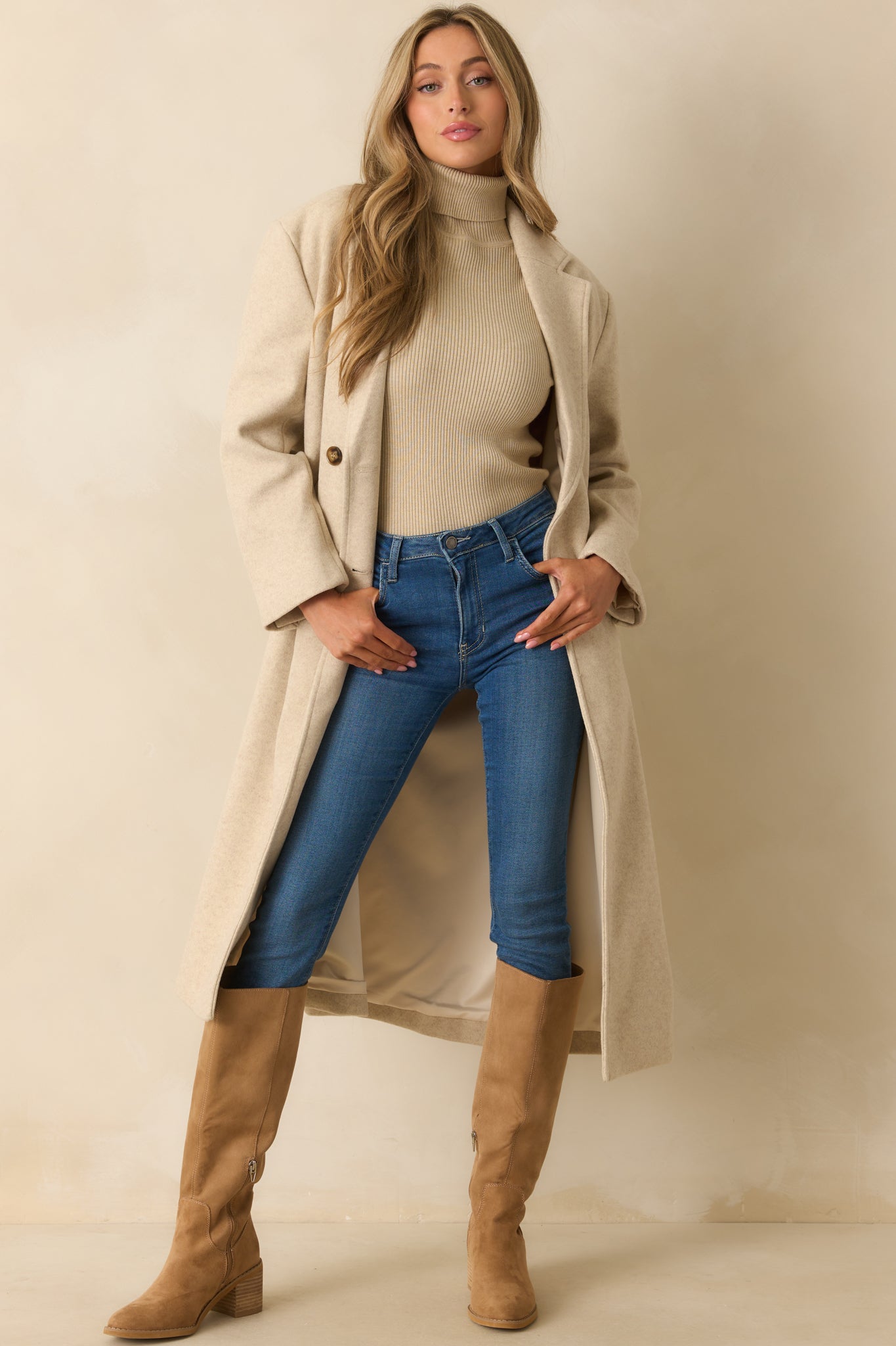 Tailored beige coat with a flowing longline silhouette and back vent for movement.