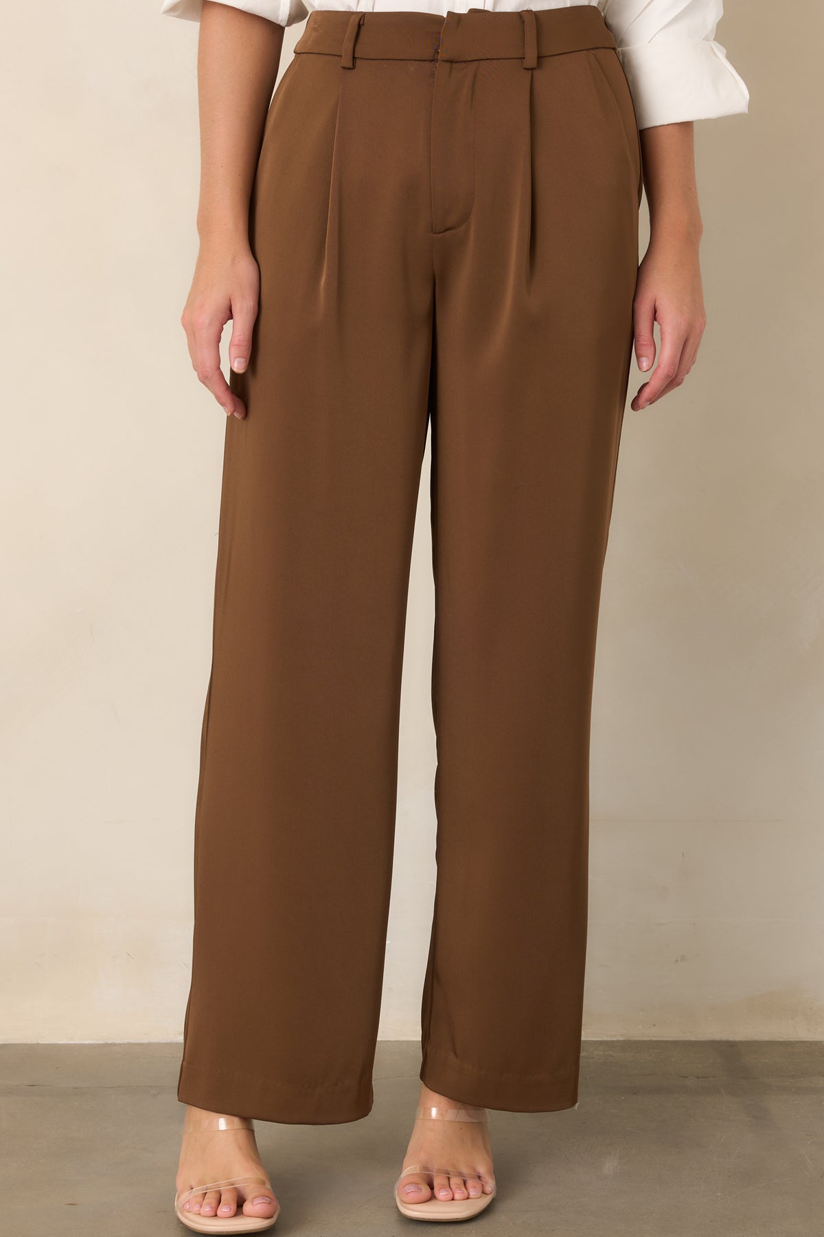 Tailored brown trousers with a concealed hook closure, zip fly, and pleated front.
