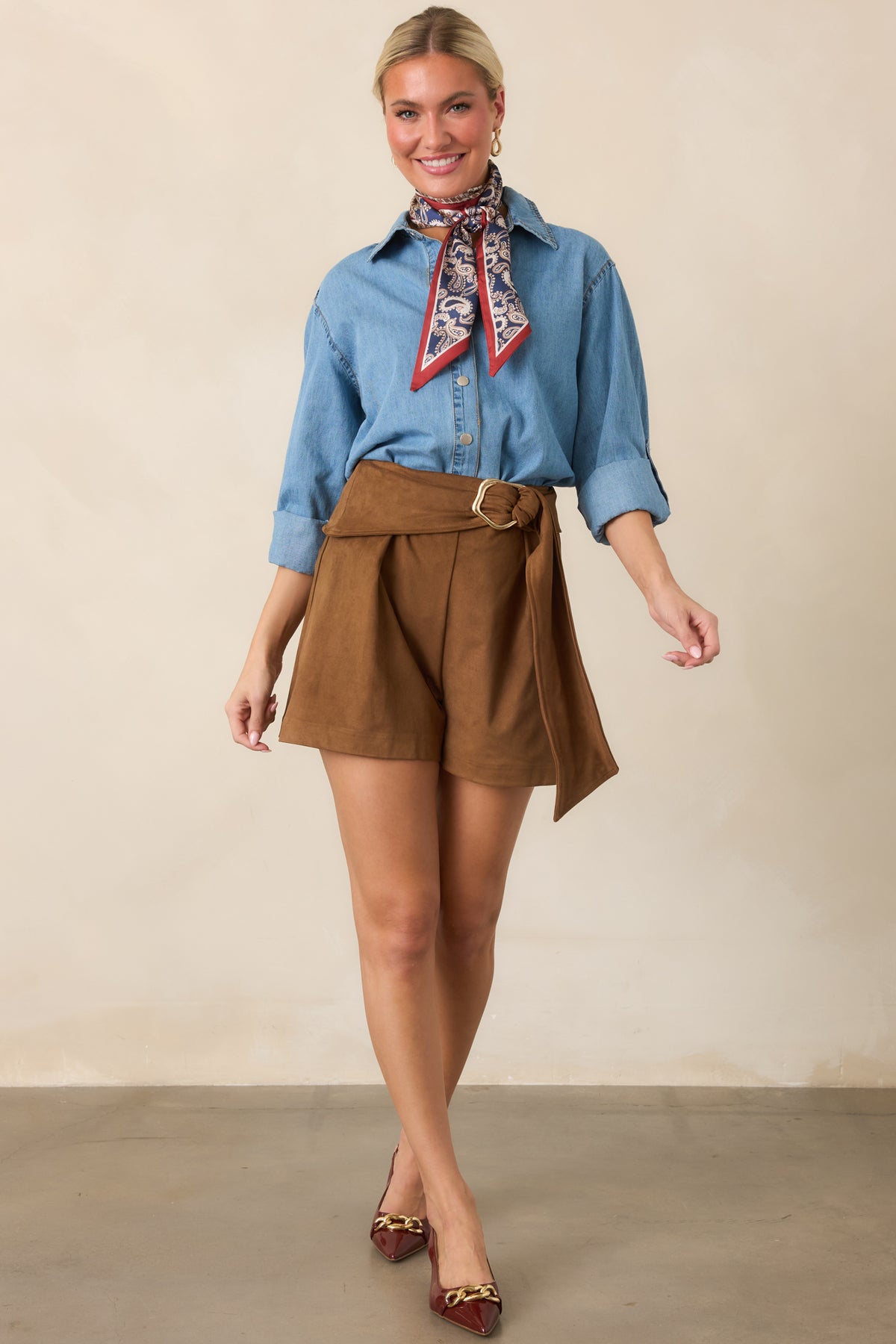 Tailored faux suede shorts defined by a wide belted waist, polished gold-tone buckle, and softly relaxed legs.