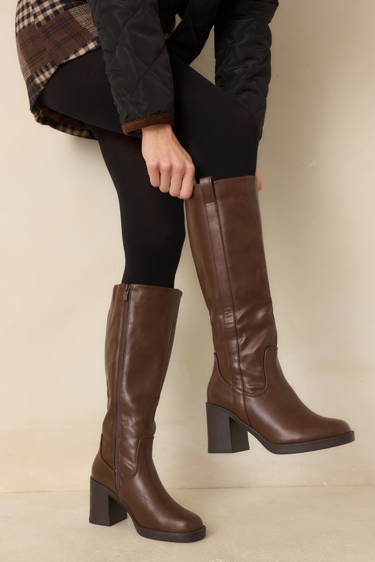 Smooth faux leather boots showcase a vertical outer shaft strap with a top pull tab and curved panel detailing.