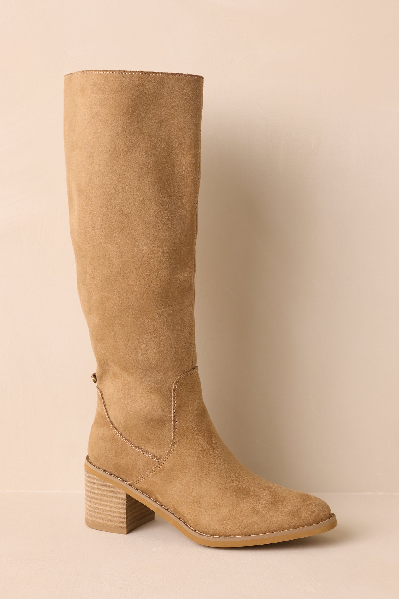 A closer detail of the tan boots showing the textured faux suede material and stitched paneling near the shaft.