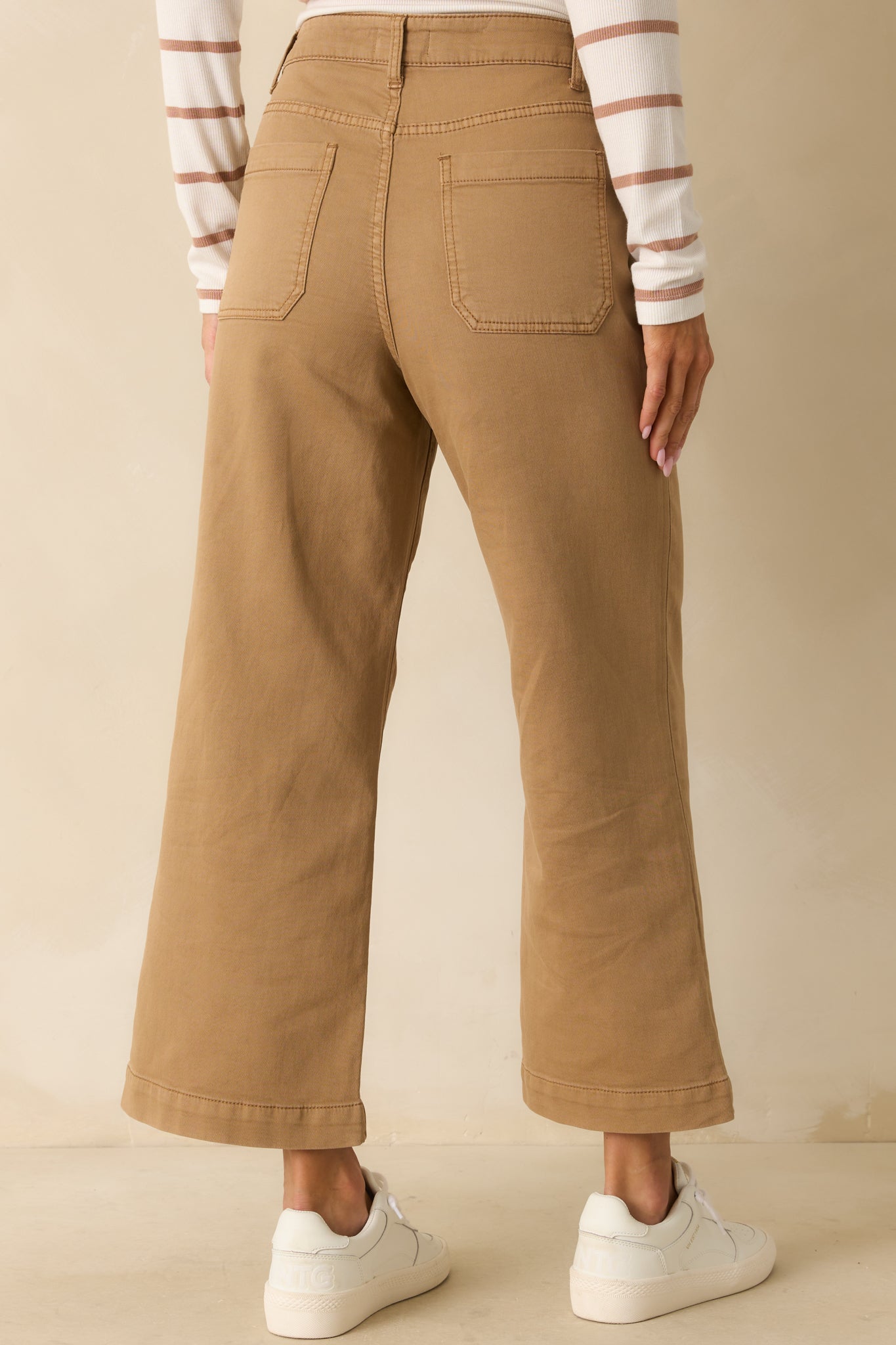 Back view of tan brown pants showing back patch pockets, wide-leg silhouette, and cropped length.
