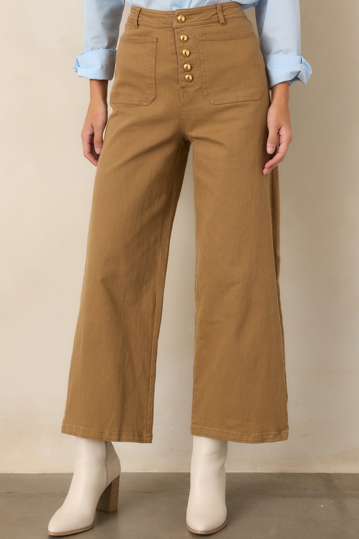 Close view of the warm tan pants showcasing the high-rise waistband and gold-tone front buttons.