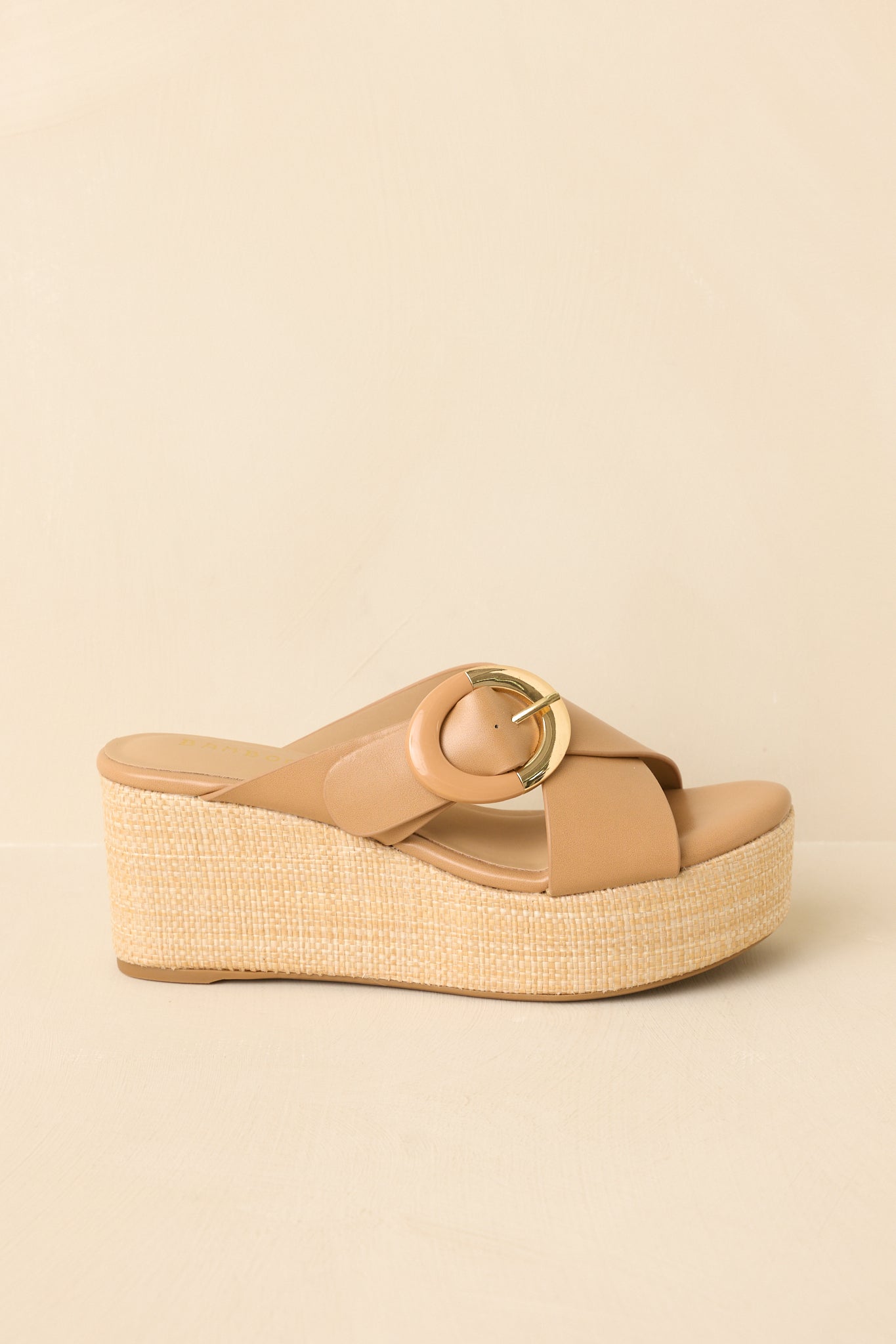 Tan platform wedge sandals displayed on a beige background, side angle showing the contrast between the smooth upper and textured sole.
