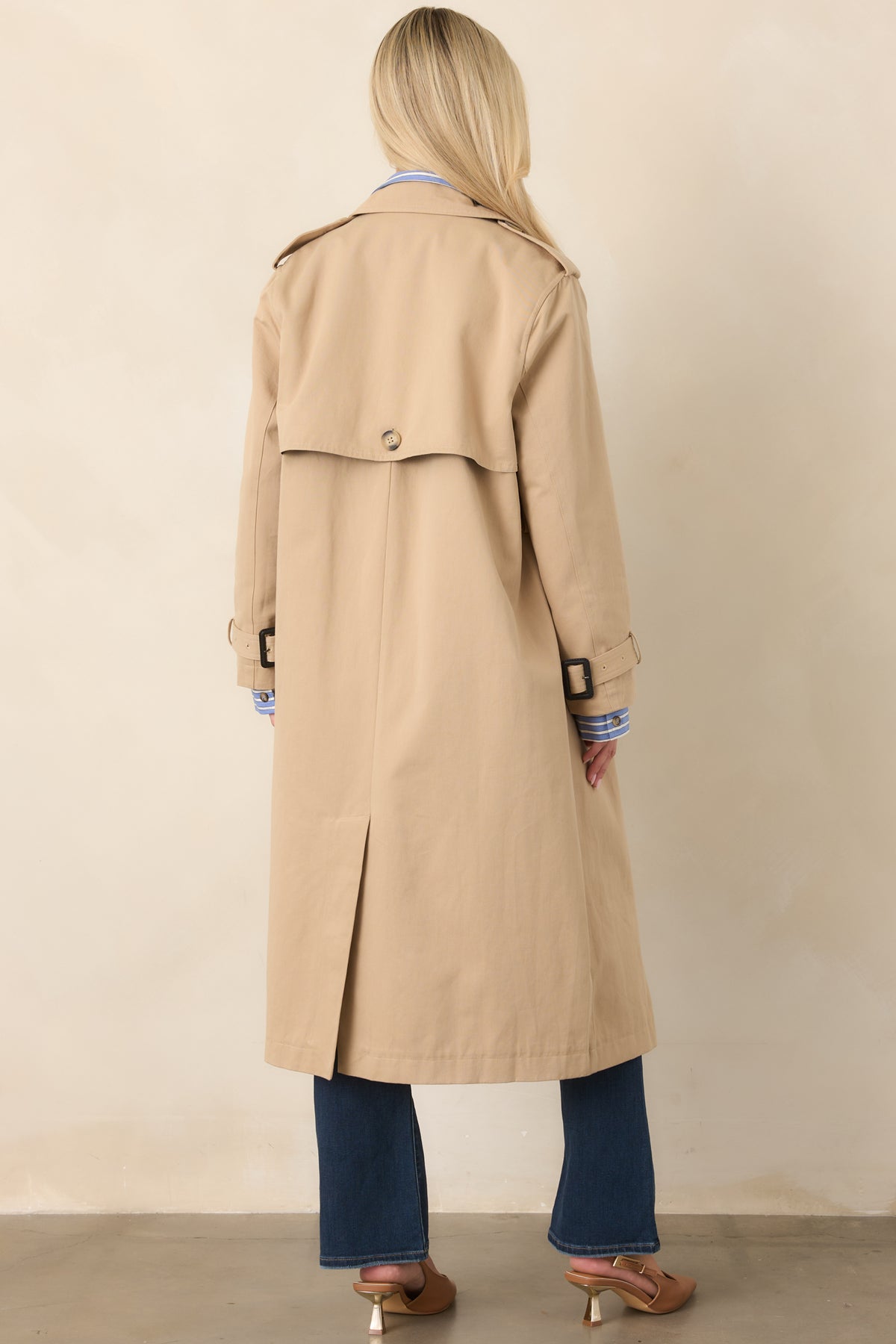Rear view of the tan trench coat showcasing the storm flap, removable tie belt, back vent, and long streamlined silhouette.
