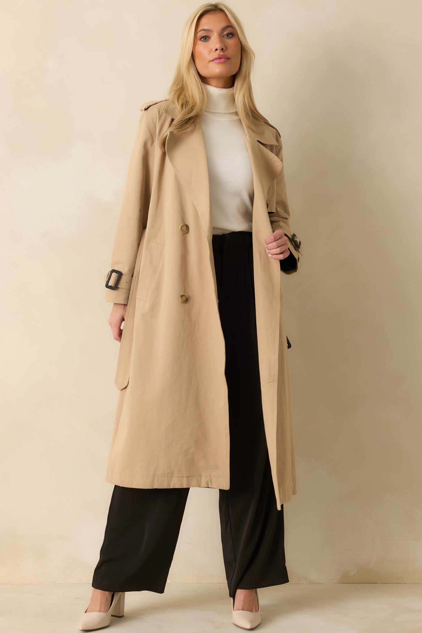 Tan trench coat with double-breasted front, notched lapels, side pockets, and removable tie belt.