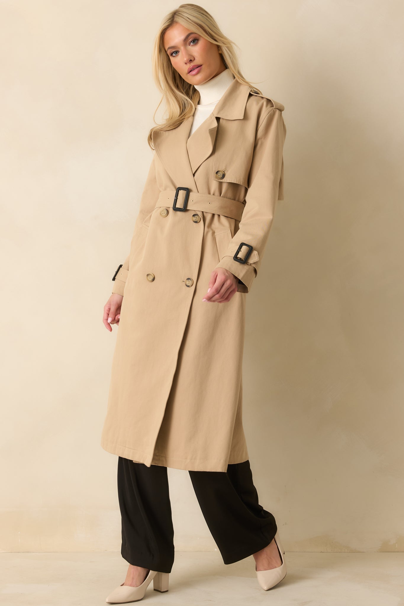 Relaxed fit tan trench coat featuring back vent, double-breasted closure, and mid-length design.