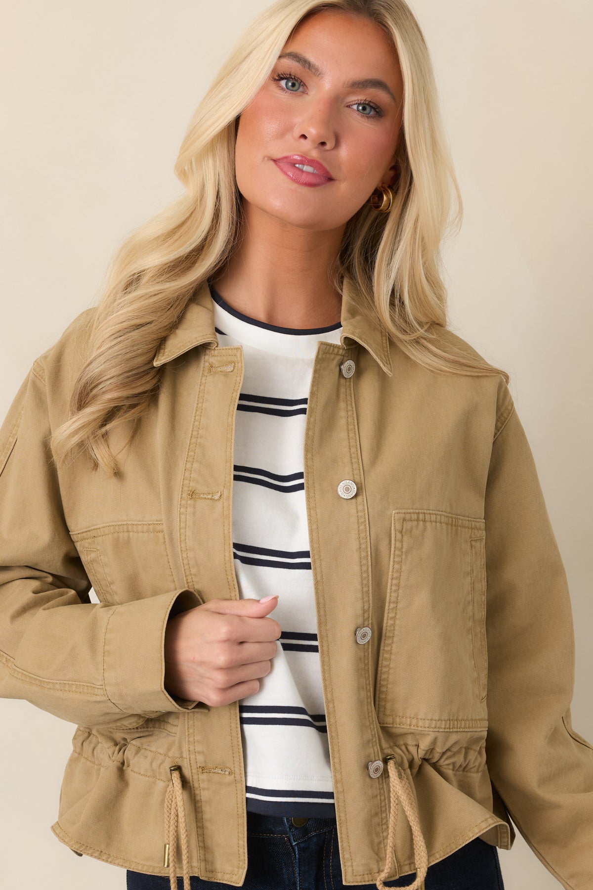 Tan utility jacket showcasing the large patch pockets and adjustable drawcord hem.