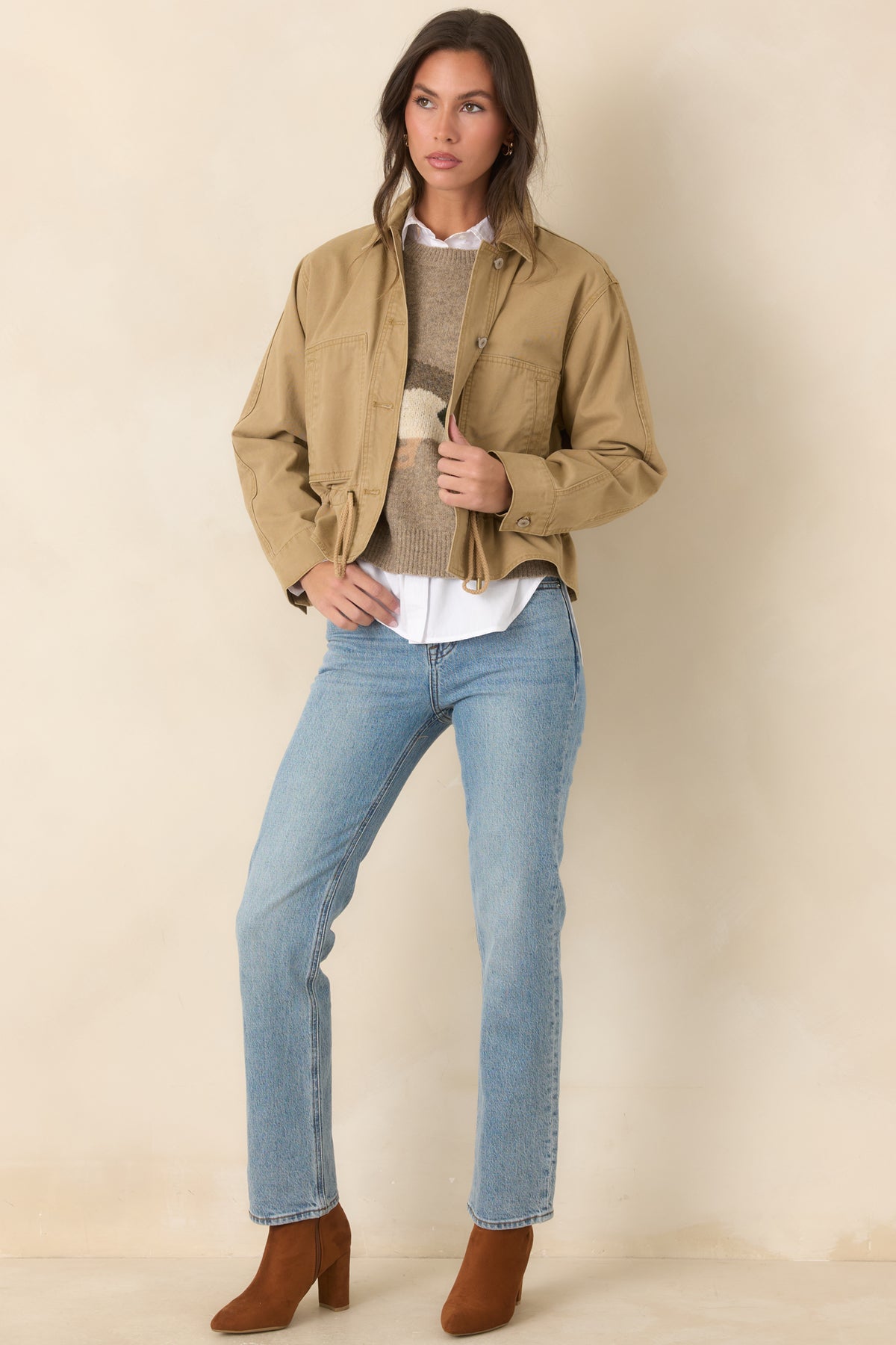 Tan utility-style jacket combines oversized patch pockets with button cuffs and a structured front closure.