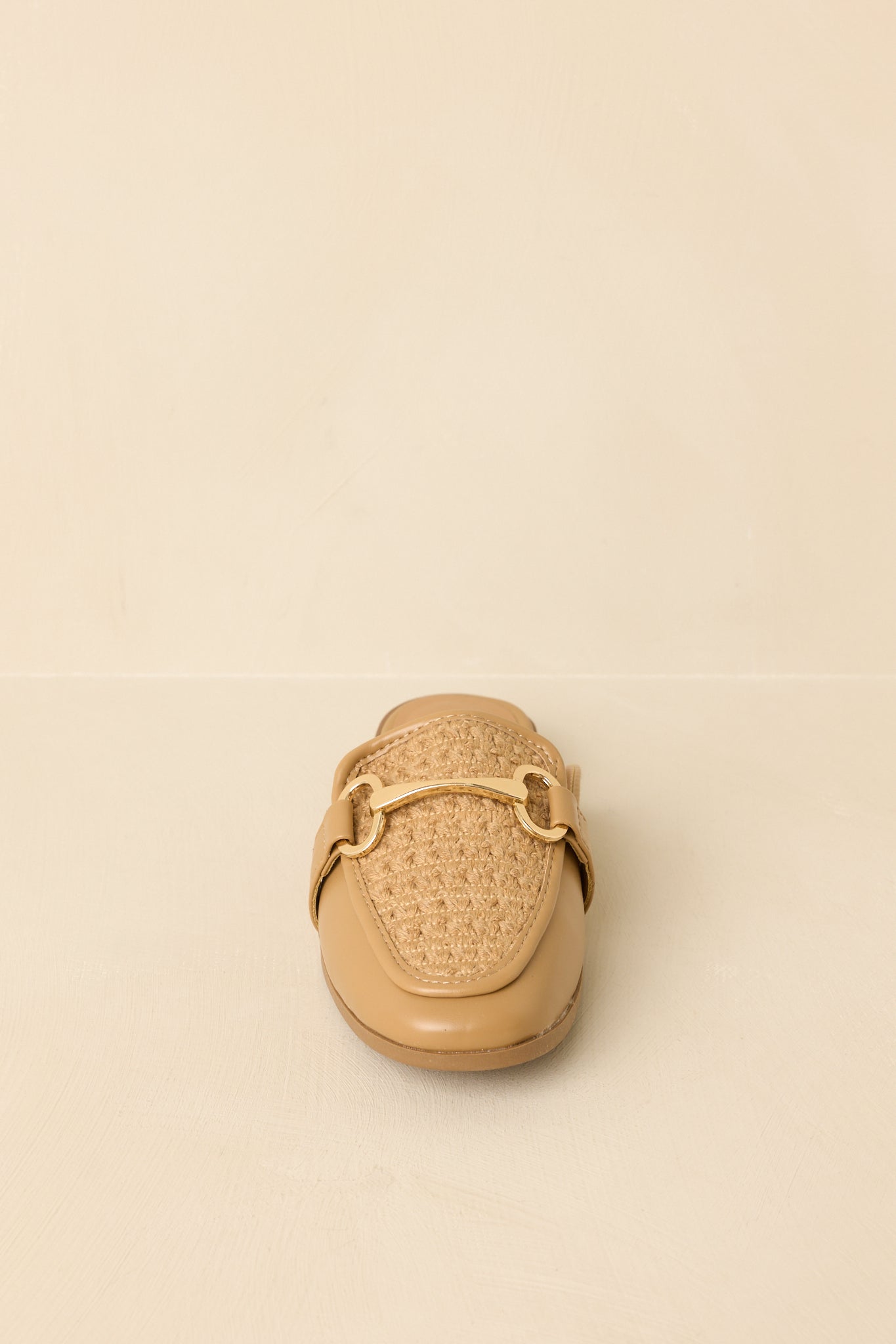 Tan woven mule loafers displayed on a beige background, showcasing slip-on design and gold hardware accent