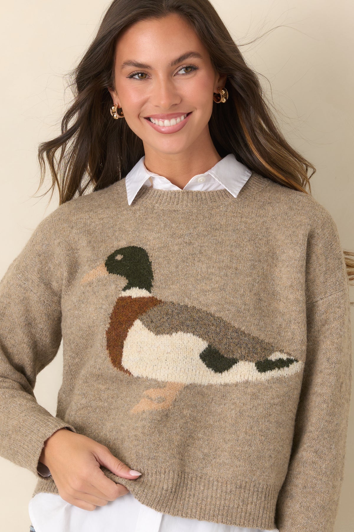 Ribbed cuffs and hem finish the relaxed silhouette of this taupe sweater with a mallard motif.